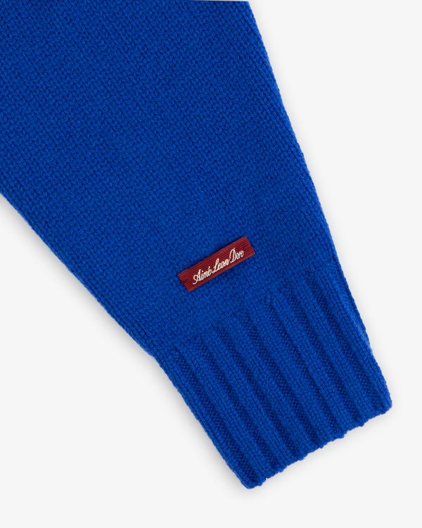 Bright blue Cashmere Crewneck Sweater sleeve with a ribbed cuff and a small red label featuring white script text.