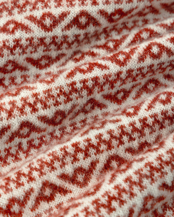 Close-up of a white Wool Cashmere Jacquard Cardigan knit fabric with a repeating rusty red geometric pattern.