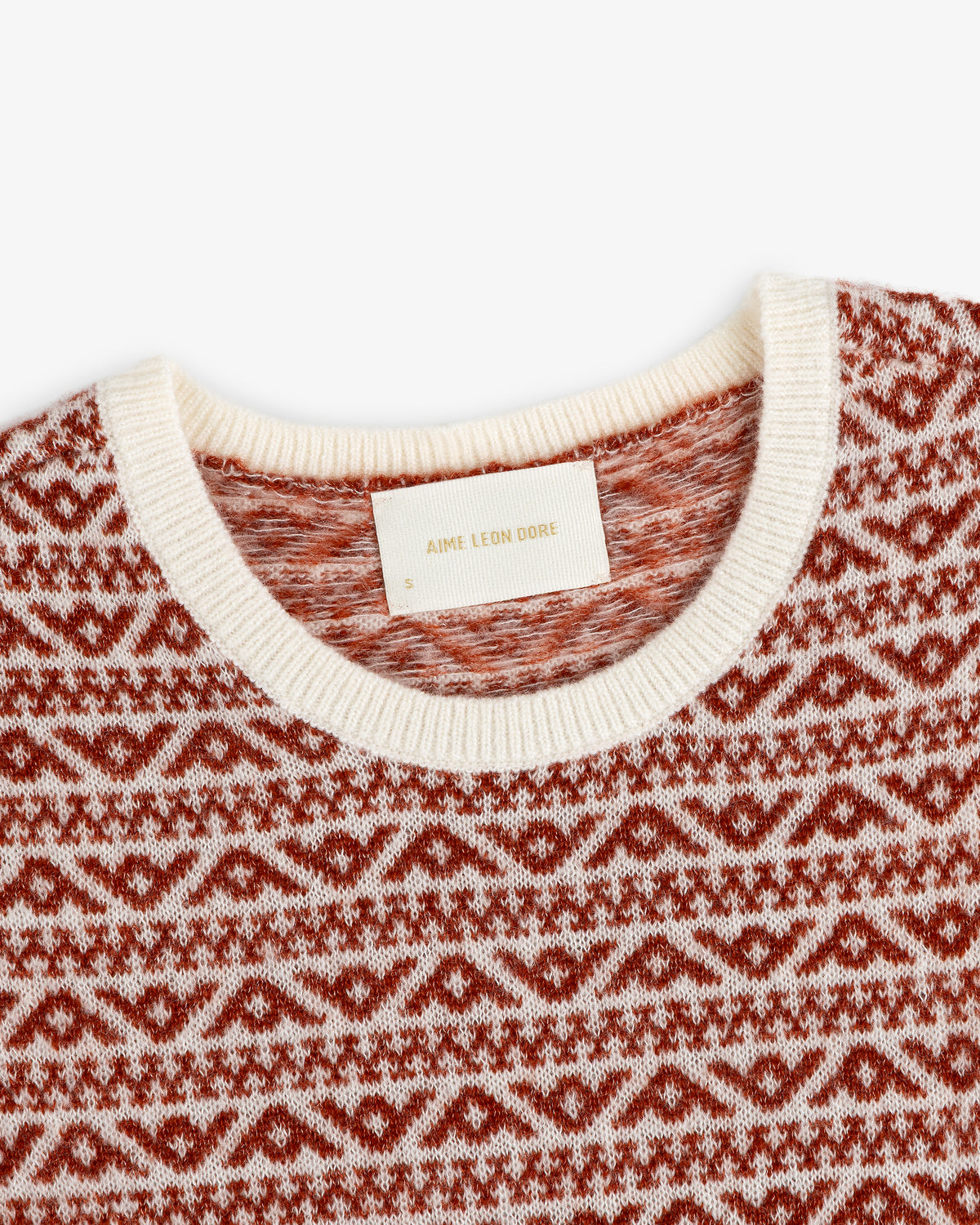Close-up of a Wool Cashmere Jacquard Shell knit crewneck sweater in a rust and cream geometric jacquard pattern.