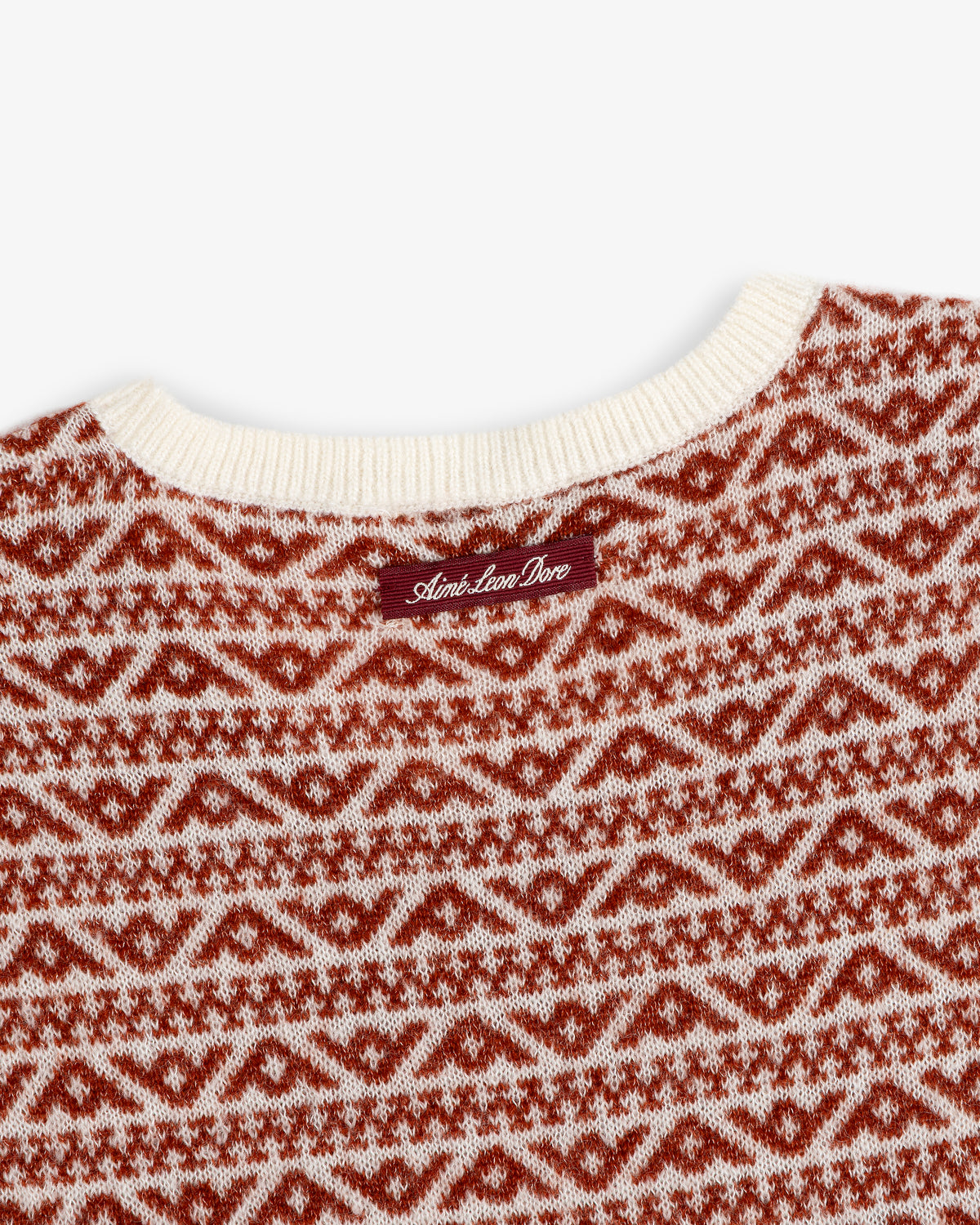Close-up of a Wool Cashmere Jacquard Shell sleeveless knit sweater in a red and cream geometric pattern with a neck label.