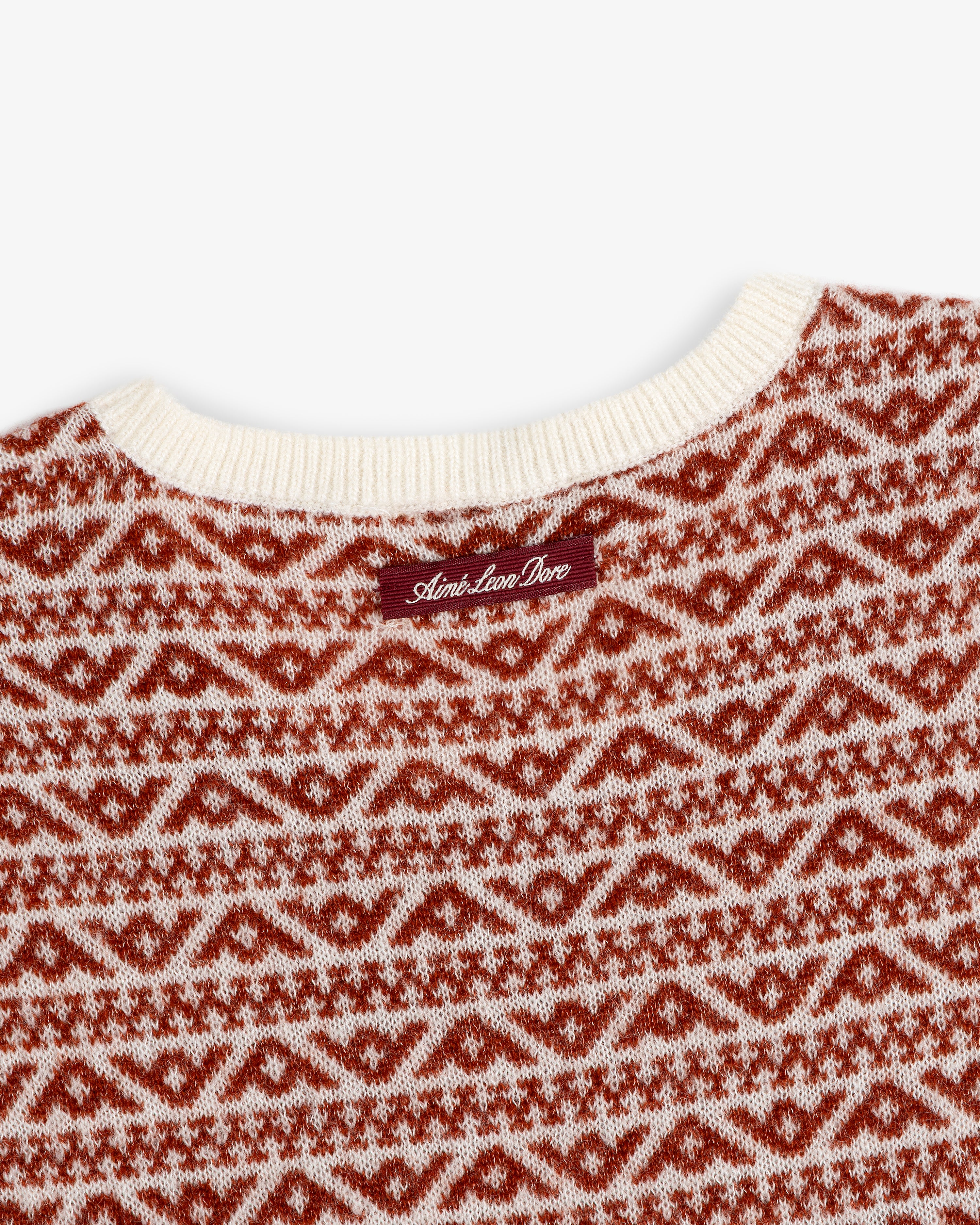 Close-up of a Wool Cashmere Jacquard Shell sleeveless knit sweater in a red and cream geometric pattern with a neck label.
