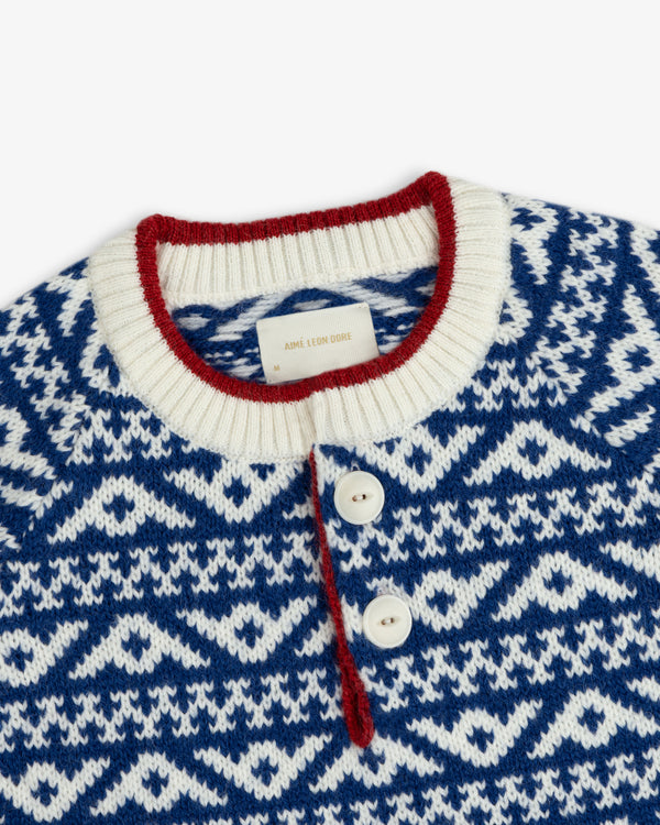 Poros Jacquard Pullover in a blue and white knit pattern with a red-trimmed collar and two-button placket.