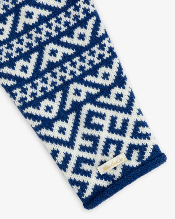 A Poros Jacquard Pullover knit sleeve with a blue and white geometric pattern and a brand tag near the cuff.