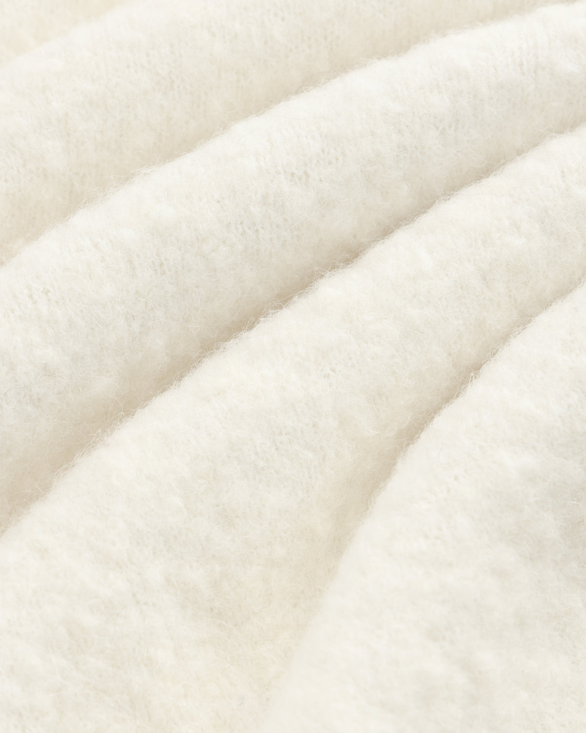 Close-up of the Alpaca Wool Quarter Zip Sweater, showcasing its white, fluffy texture and cozy, wavy folds.