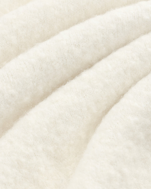 Close-up of the Alpaca Wool Quarter Zip Sweater, showcasing its white, fluffy texture and cozy, wavy folds.
