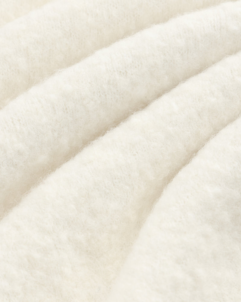 Close-up of the Alpaca Wool Quarter Zip Sweater, showcasing its white, fluffy texture and cozy, wavy folds.