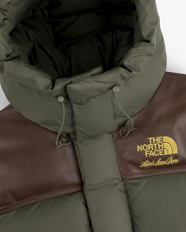 Close-up of ALD / The North Face Baltoro Jacket in green and brown with yellow embroidered logos.