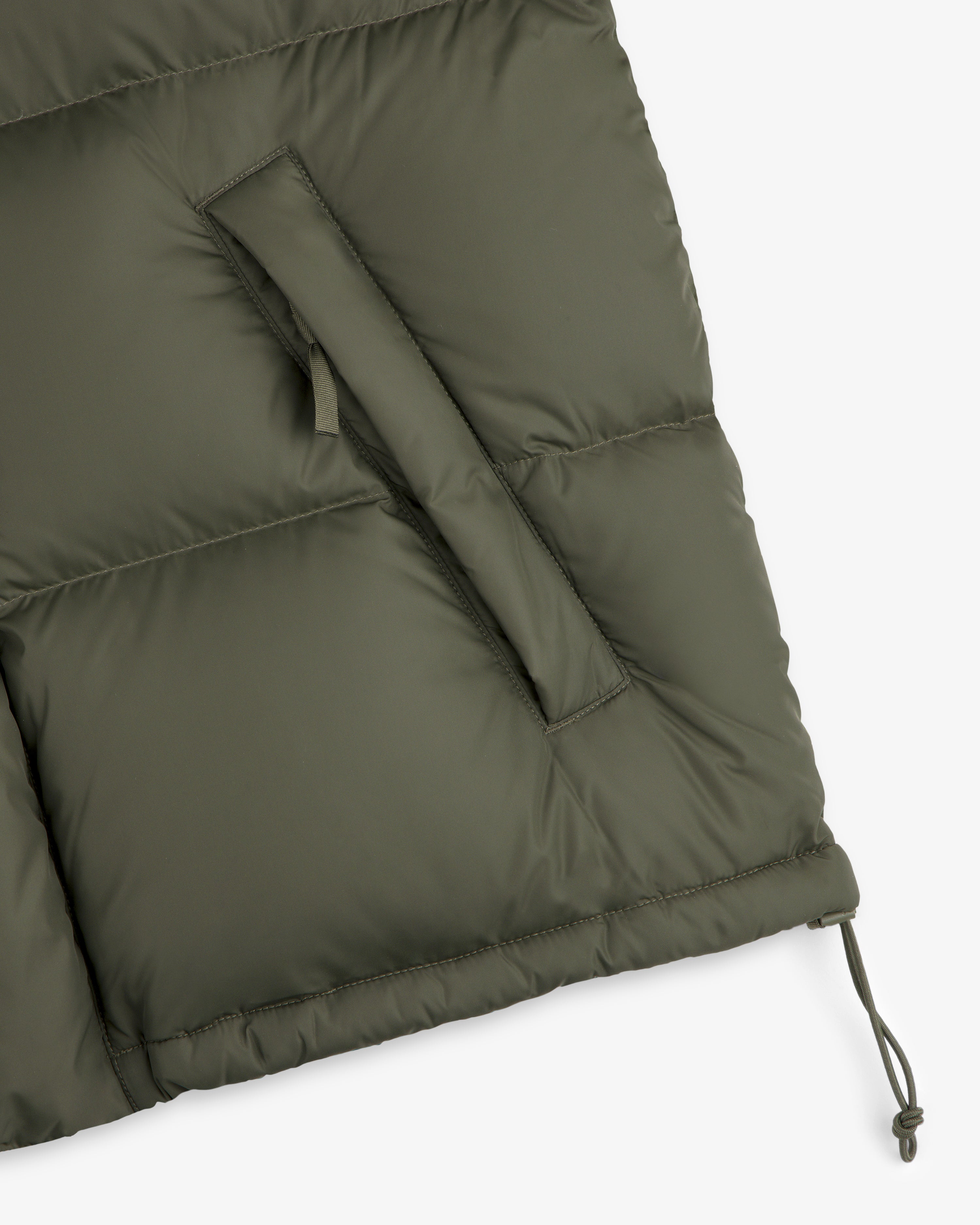 Close-up of the ALD / The North Face Baltoro Jacket in olive with a zippered pocket and adjustable drawstring hem.
