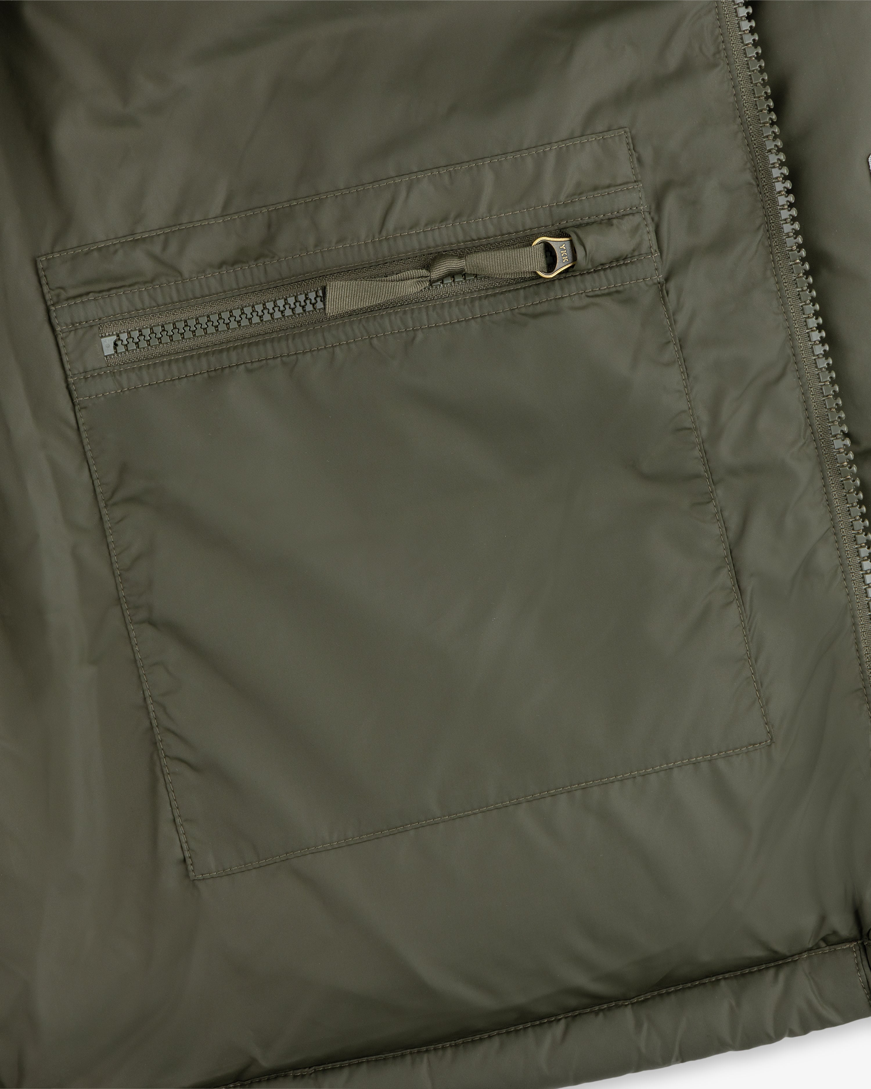Close-up of an ALD / The North Face Baltoro Jacket pocket with a horizontal zipper and visible stitching.