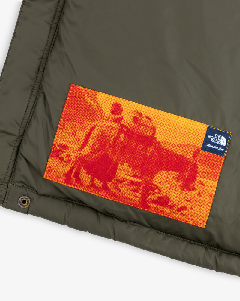 ALD / The North Face Baltoro Jacket: olive fabric, orange patch with person & donkey, small North Face logo tag.