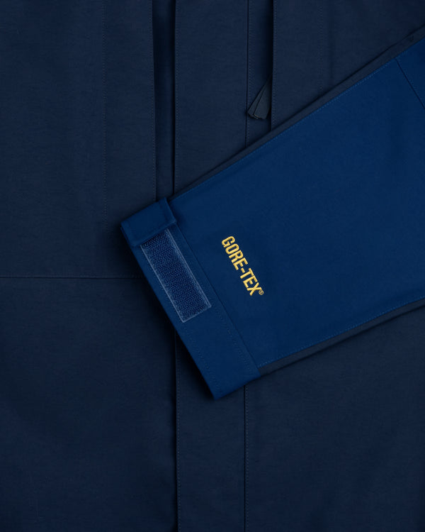Close-up of ALD/The North Face GORE-TEX 2000 Mountain Jacket sleeve with Velcro cuff on matching blue background.