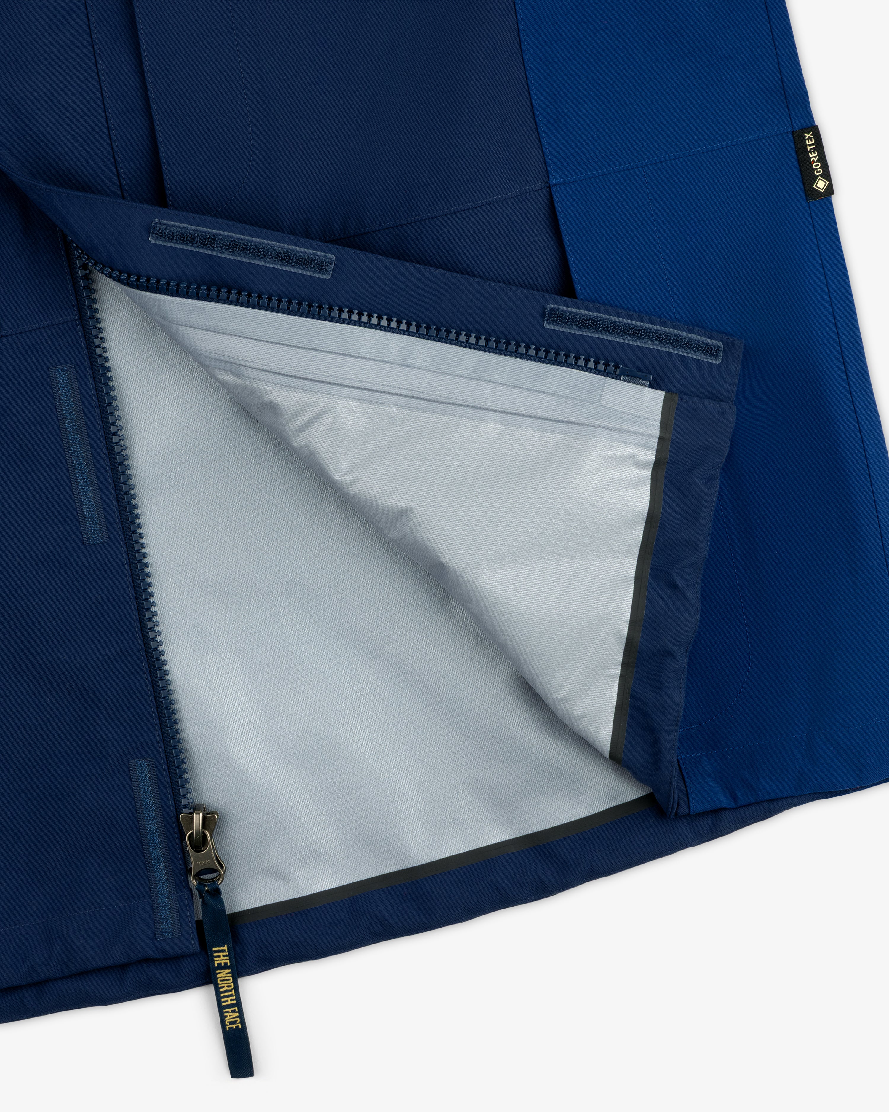 Close-up of ALD/The North Face GORE-TEX 2000 Mountain Jacket’s blue exterior, gray lining, and half-unzipped zipper.