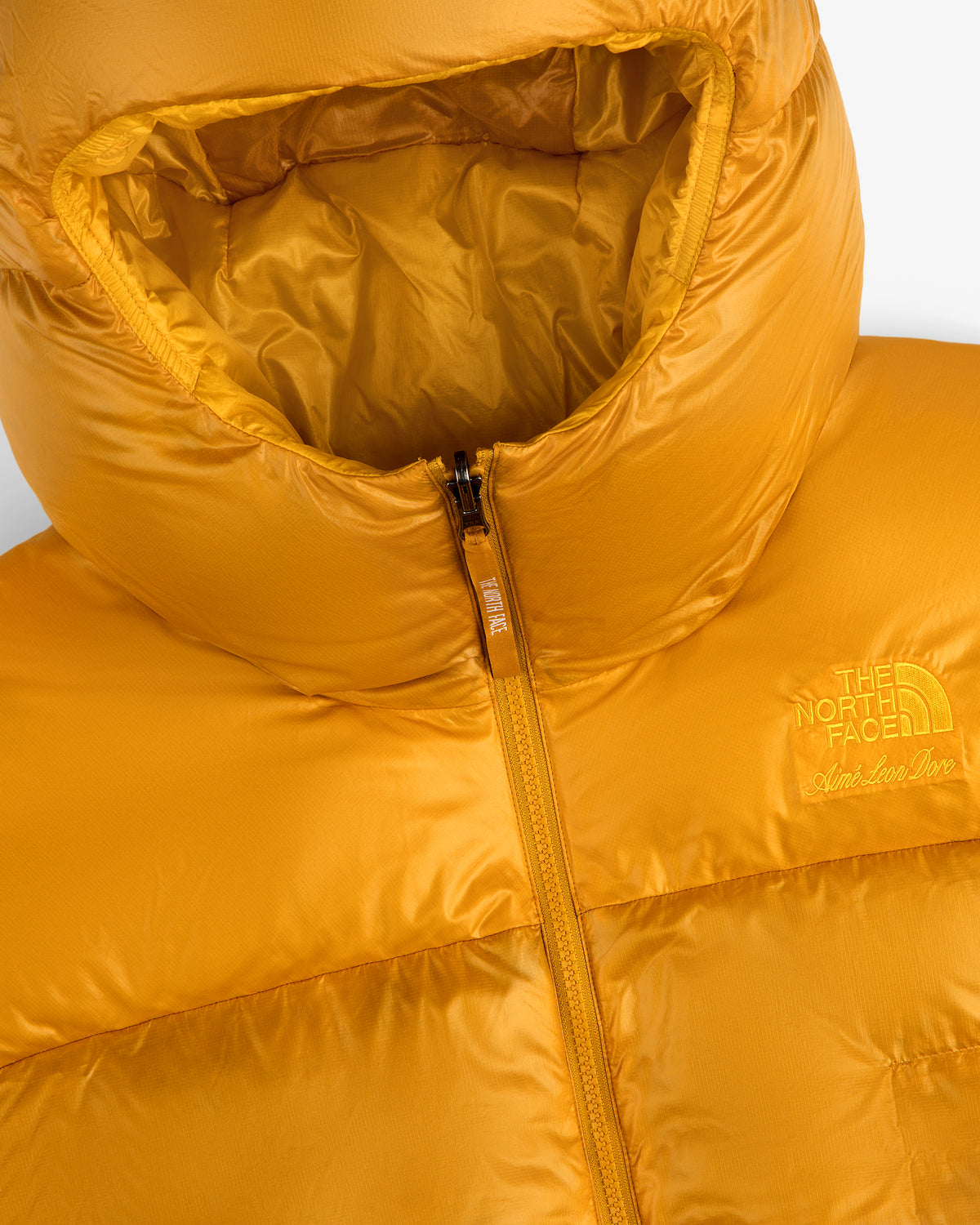 Close-up of the ALD / The North Face Reversible Pertex® Nuptse Jacket in orange, featuring a hood and front zipper.