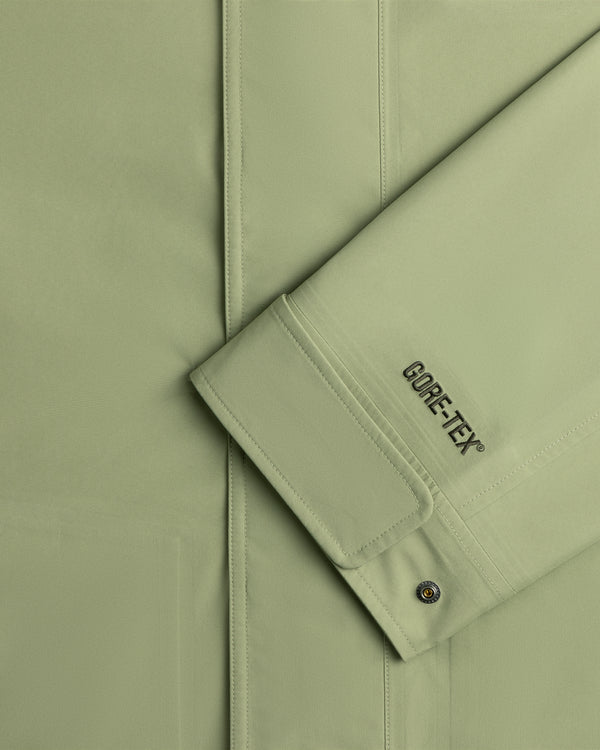 Close-up of a light green ALD/The North Face GORE-TEX Trench Coat sleeve with seam and metal snap button on cuff.