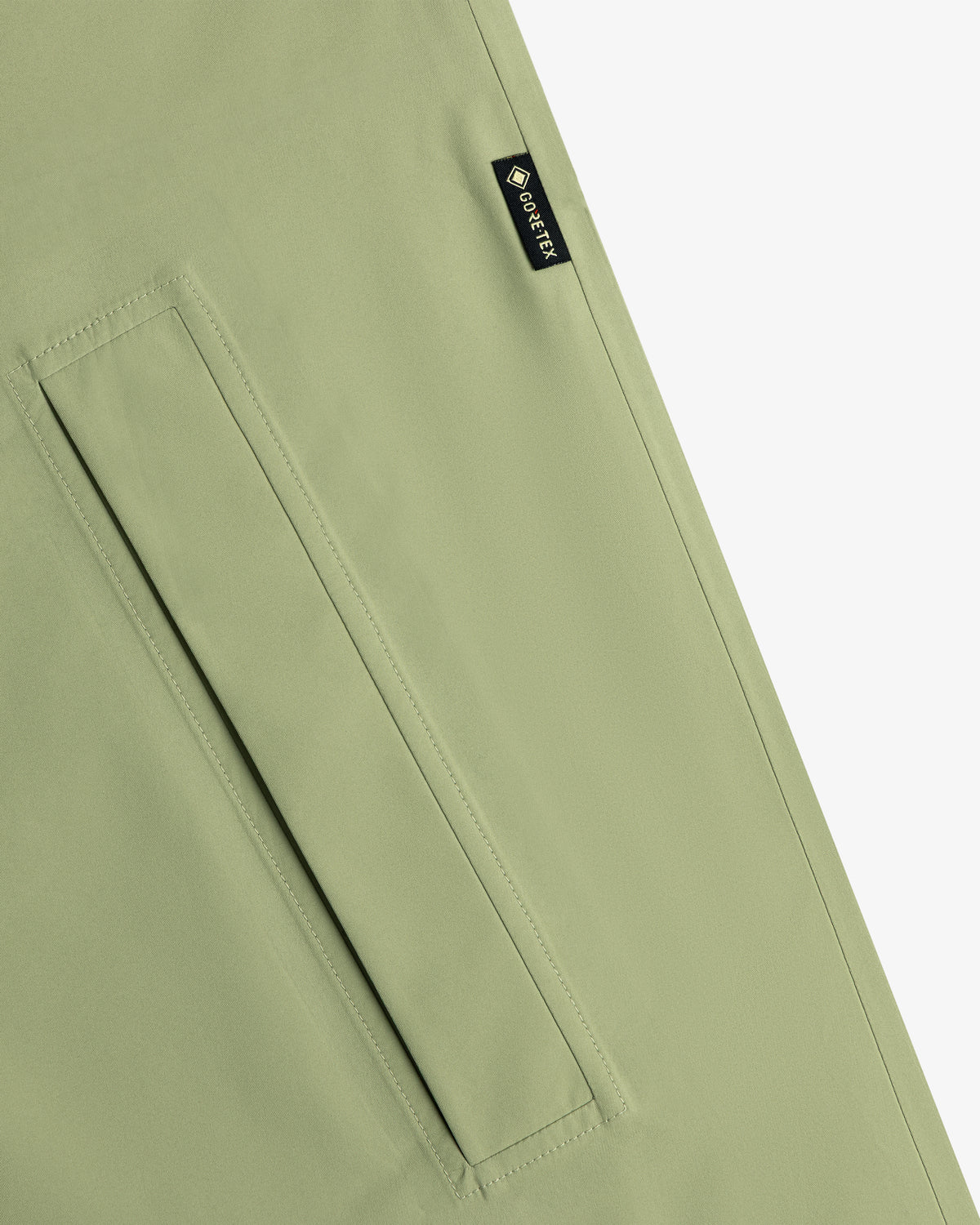 Close-up of the ALD/The North Face GORE-TEX Trench Coat in light green with a rectangular pocket and black GORE-TEX label.