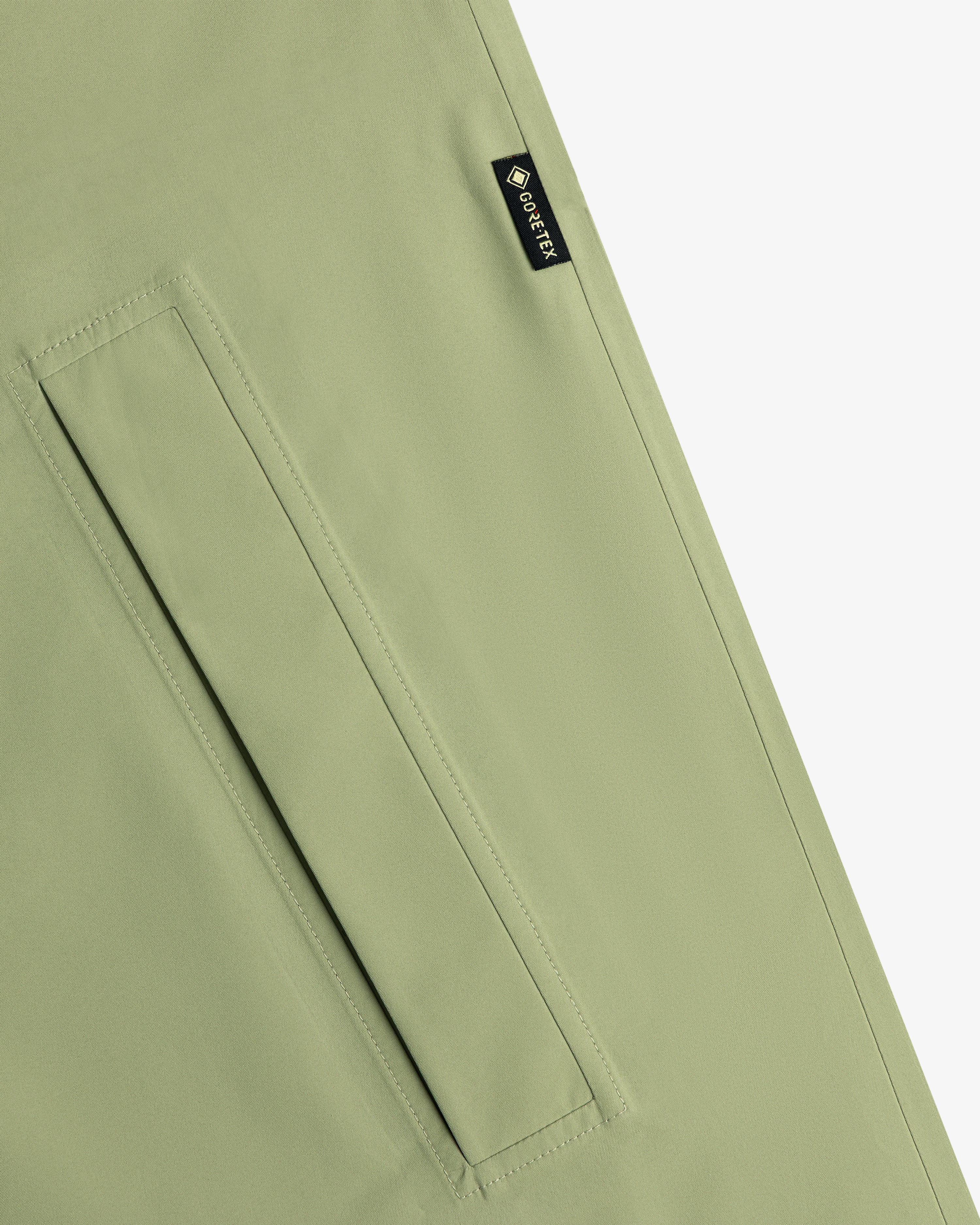 Close-up of the ALD/The North Face GORE-TEX Trench Coat in light green with a rectangular pocket and black GORE-TEX label.