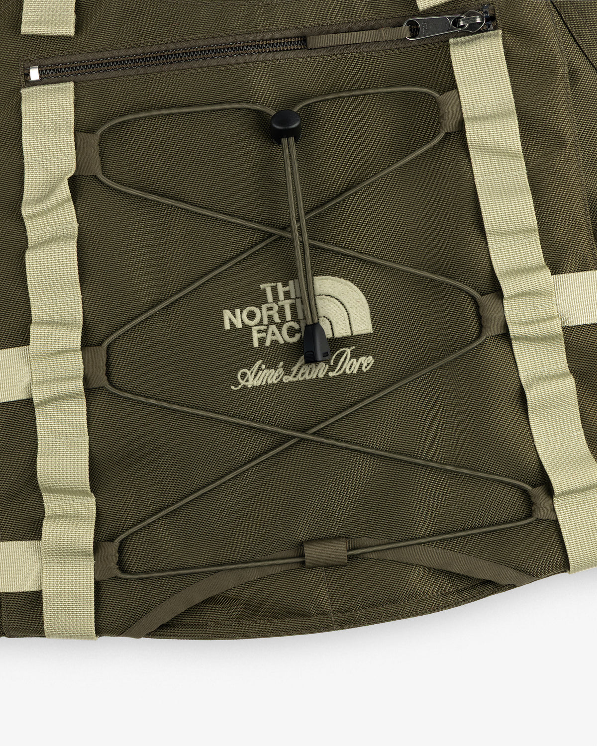 Close-up of an olive green ALD / The North Face Ballistic Tech Vest with cream accents and visible logo.