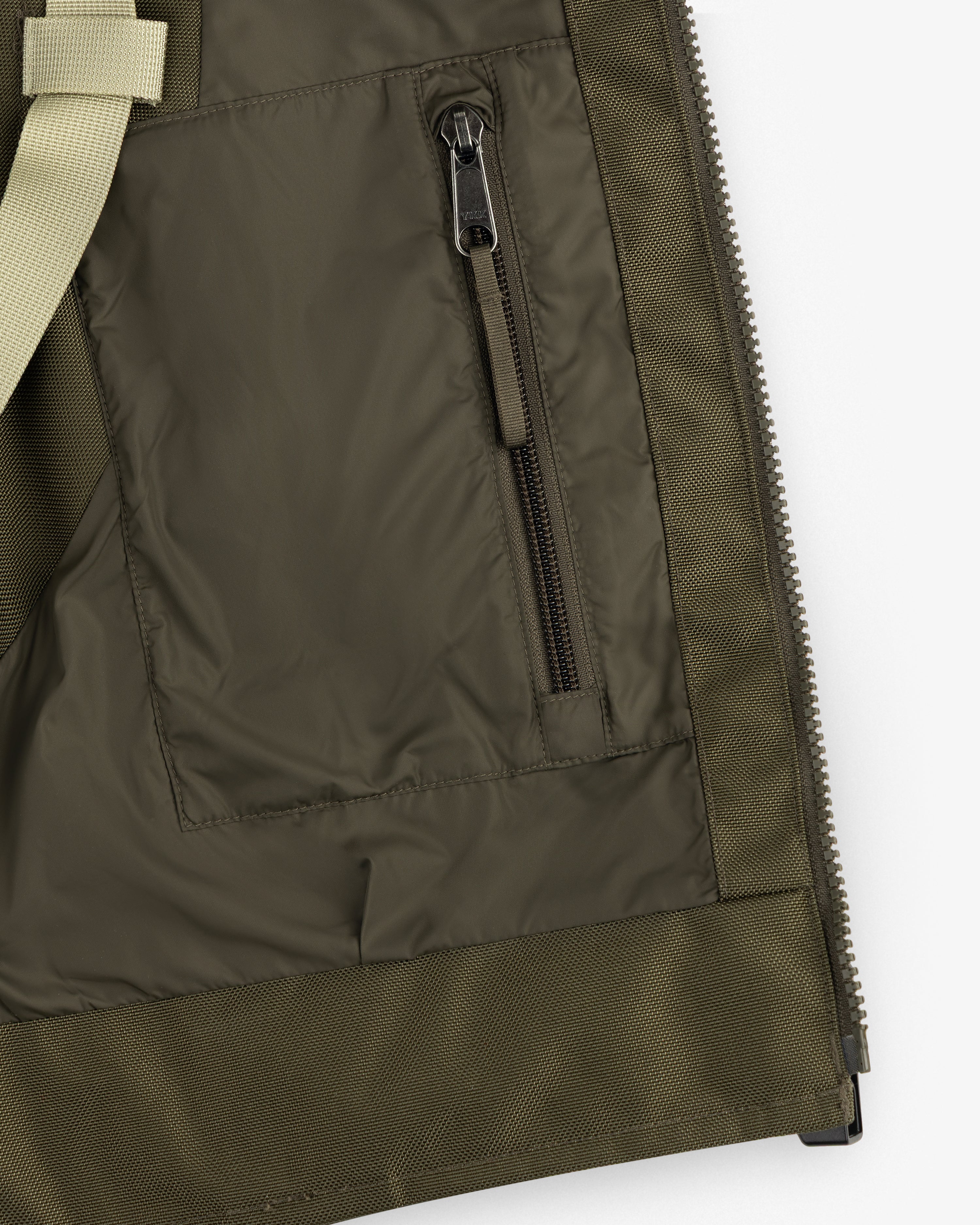 Close-up of the ALD/The North Face Ballistic Tech Vest pocket with black zipper and beige strap detail.