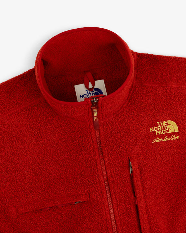 Close-up of a red ALD / The North Face ’95 Denali Half-Zip Fleece Pullover with yellow embroidery and chest zip.