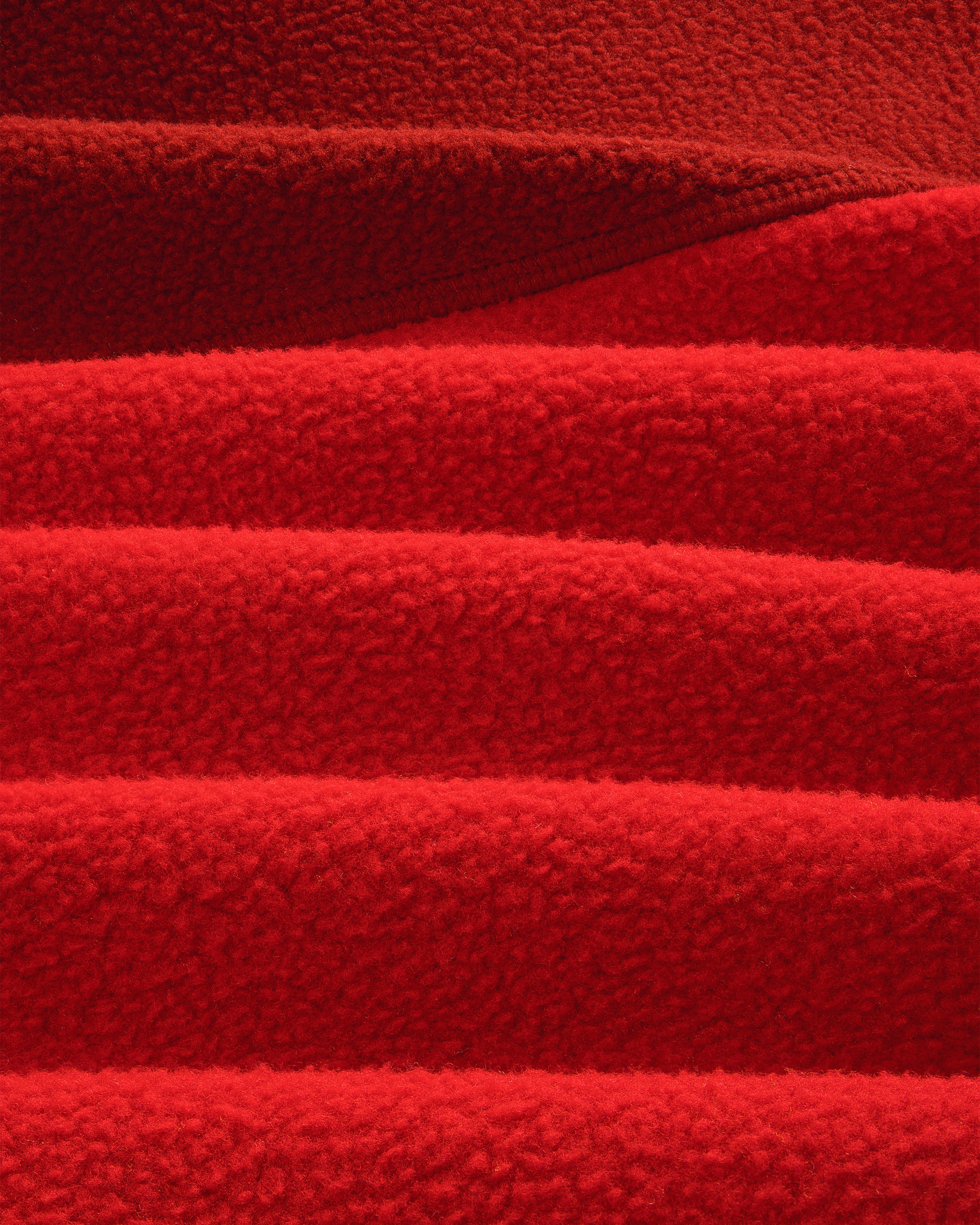Close-up of ALD/The North Face ’95 Denali Half-Zip Fleece, showing red fabric’s soft, textured ridges and shadows.