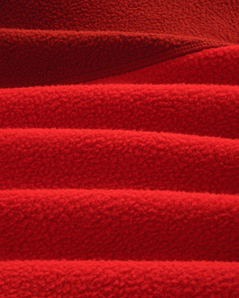 Close-up of ALD/The North Face ’95 Denali Half-Zip Fleece, showing red fabric’s soft, textured ridges and shadows.
