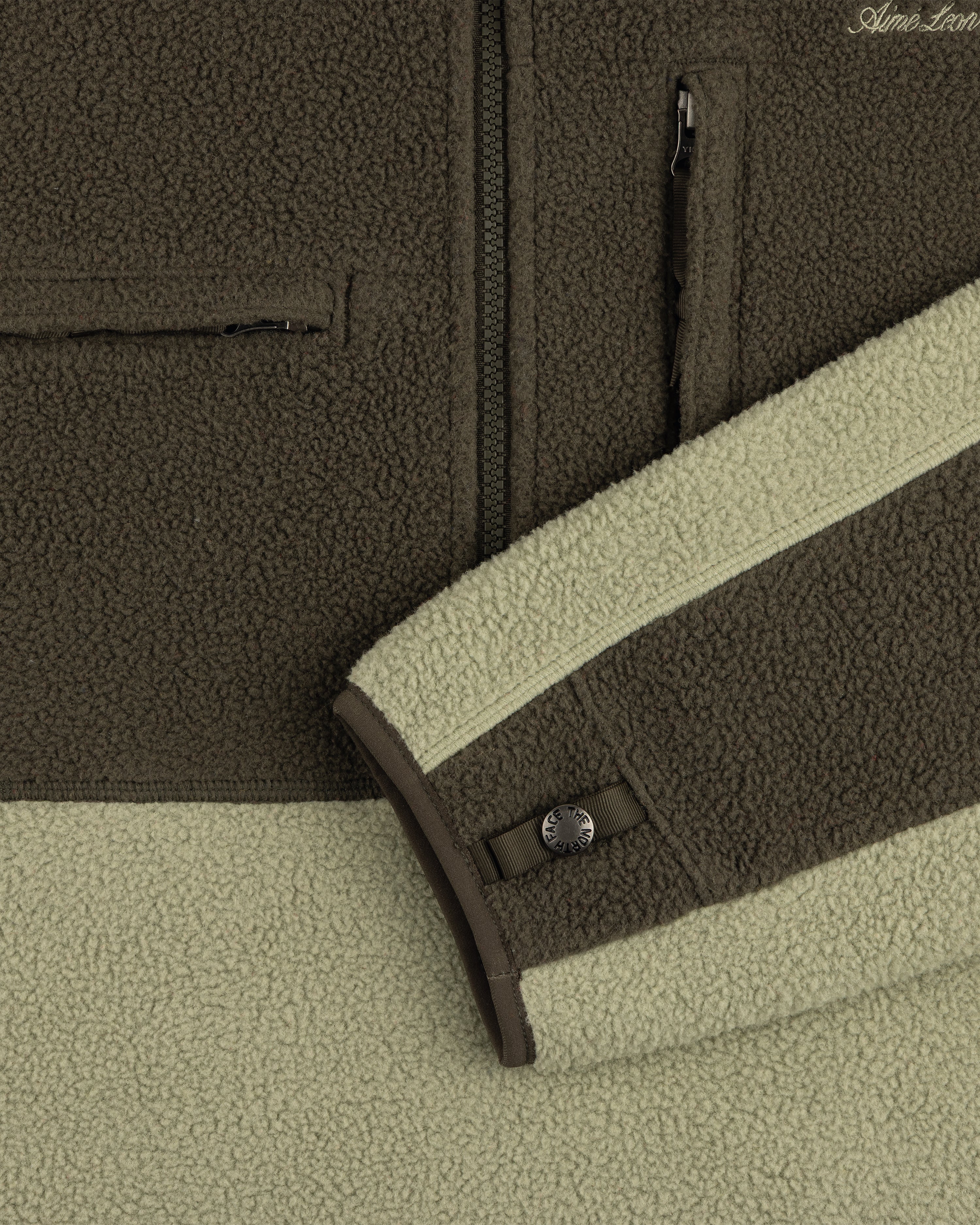 Close-up of ALD / The North Face ’95 Denali Half-Zip in two greens, with zip pockets and snap cuff detail.