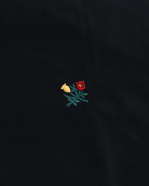 Small red and yellow floral embroidery with green leaves on the black Crest Nylon Windbreaker.