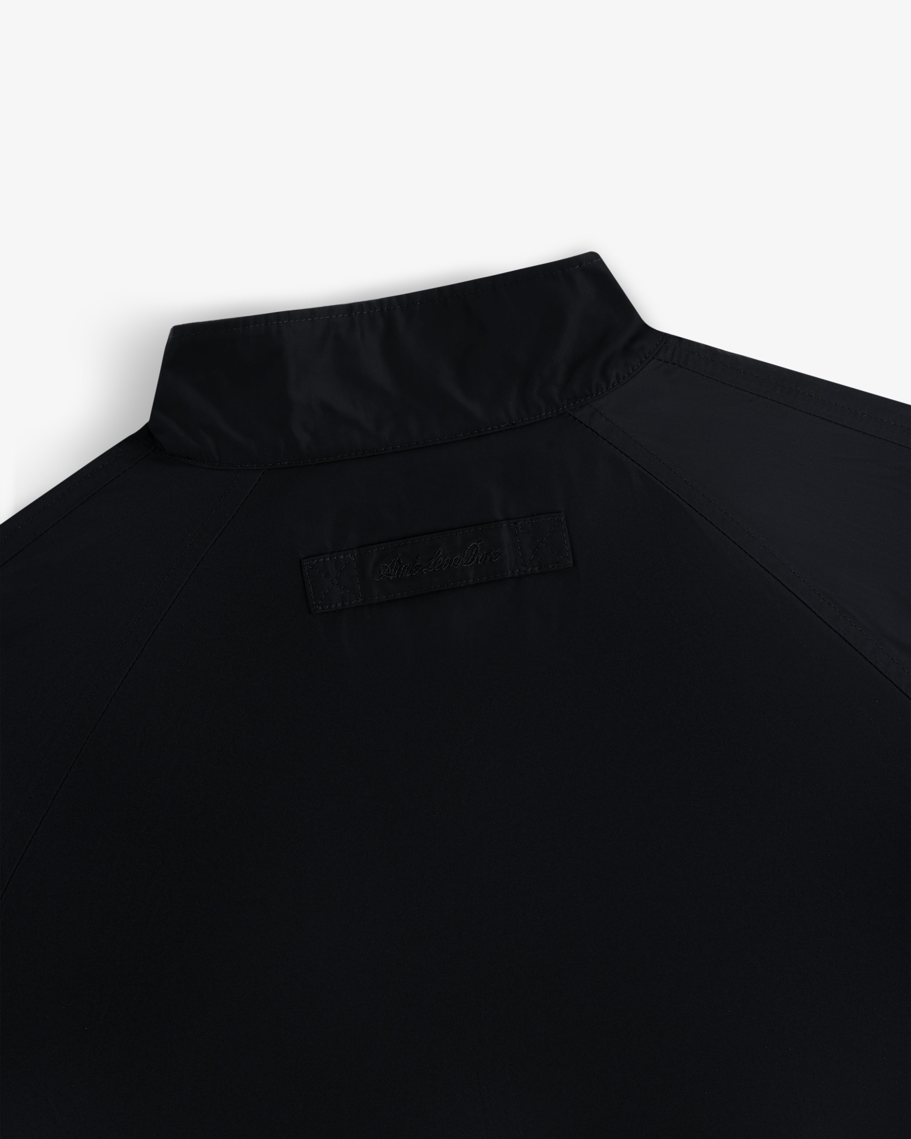 Close-up of the Crest Nylon Windbreaker’s upper back, highlighting its collar and a stitched rectangular patch below.