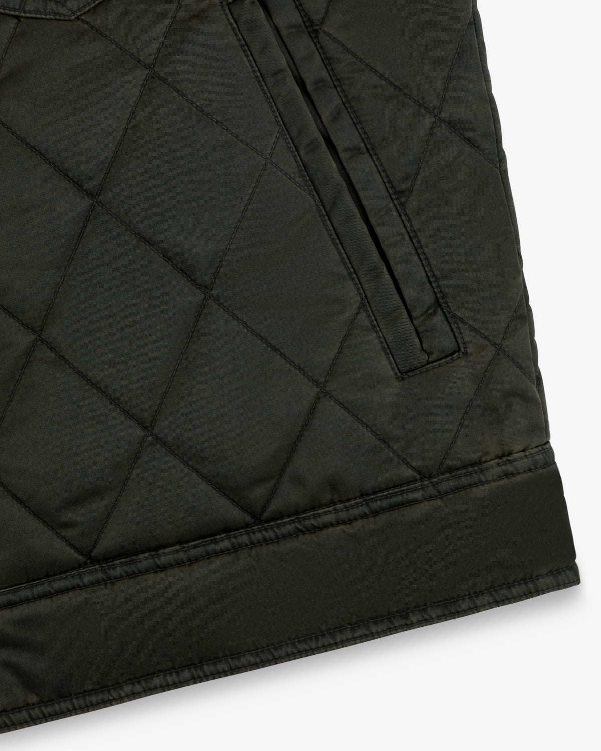 Close-up of a dark olive Quilted Trucker Jacket featuring a side pocket and a wide hem band.