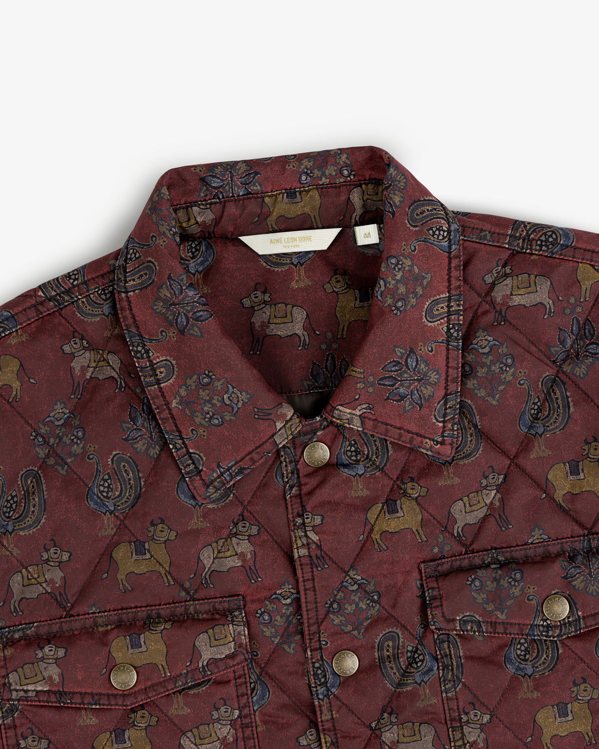 Quilted Trucker Jacket in maroon featuring a repeating pattern of cows, roosters, and floral motifs.