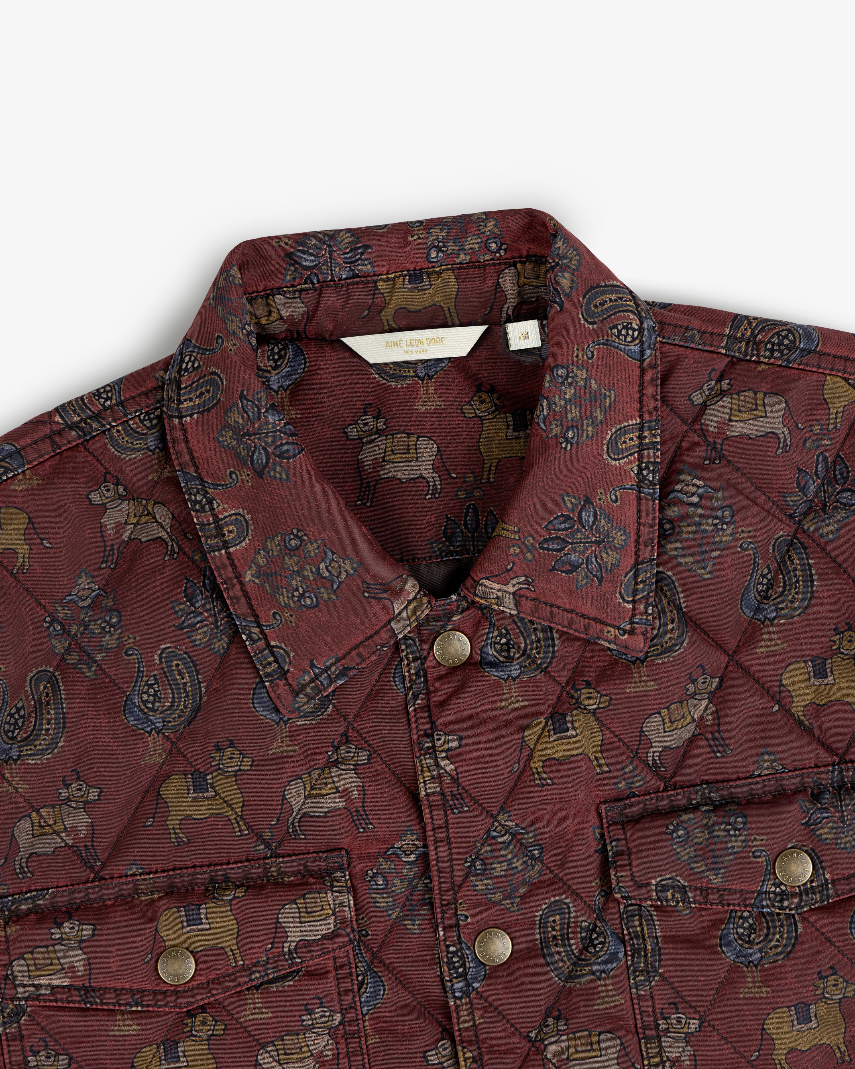 Quilted Trucker Jacket in maroon featuring a repeating pattern of cows, roosters, and floral motifs.