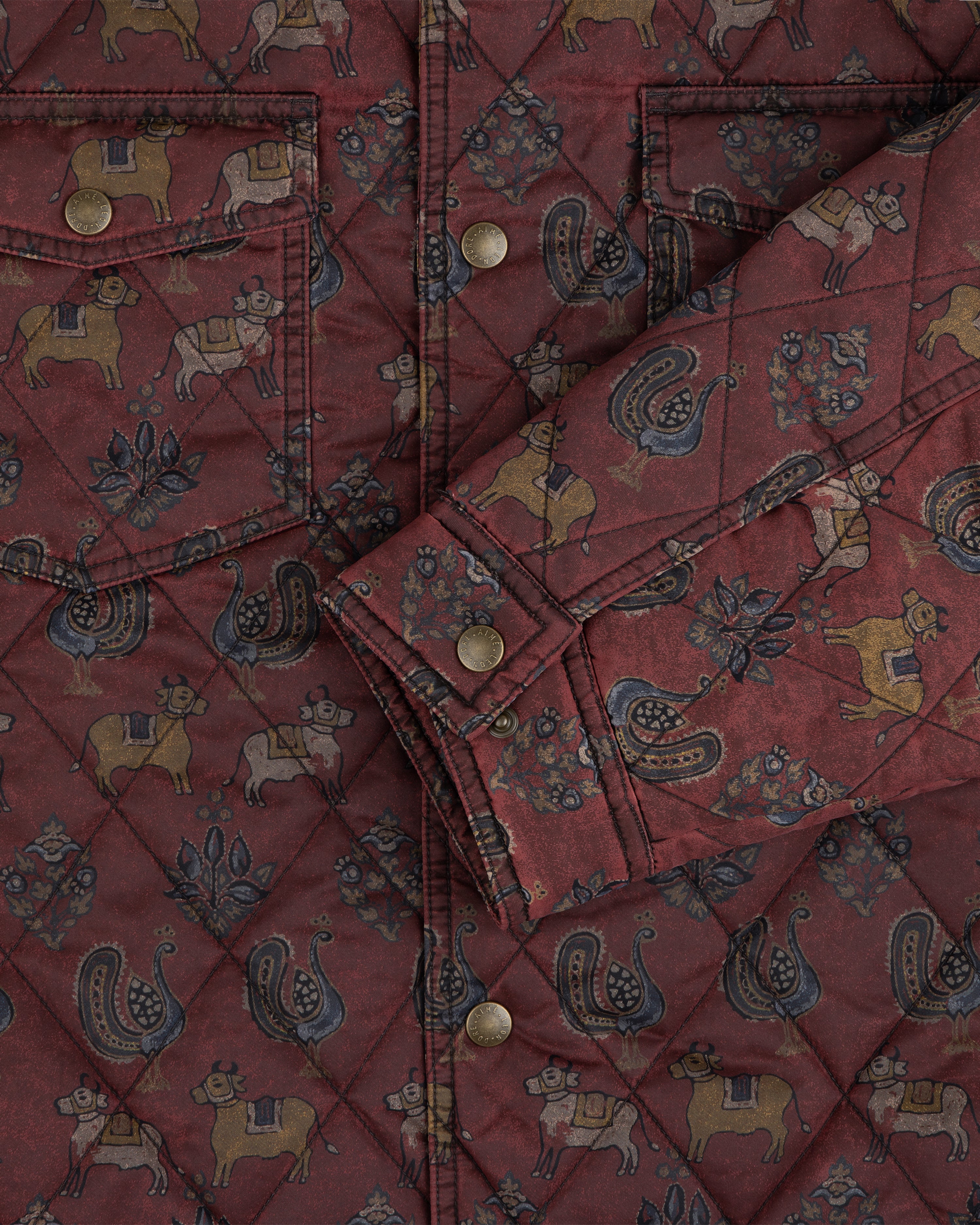 Quilted Trucker Jacket in maroon, featuring a repeating pattern of animals, floral motifs, and metal buttons.