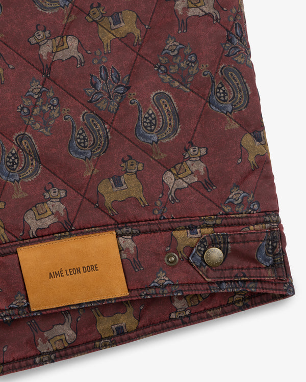 Quilted Trucker Jacket in maroon with a cattle and bird print and a tan leather brand label at the hem.