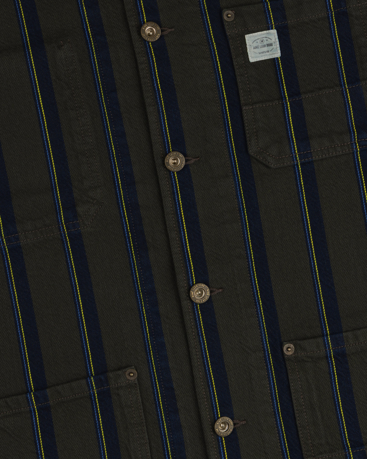 Close-up of a Striped Denim Chore Jacket with buttons, chest pockets, and a small light fabric label.