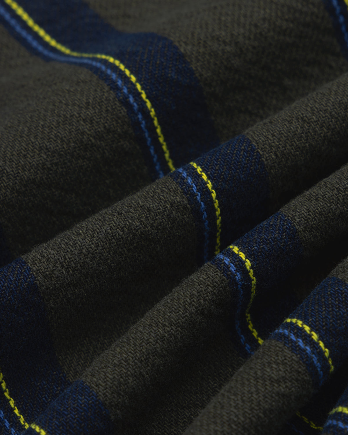 Close-up of Striped Denim Chore Jacket fabric with blue and yellow plaid stripes, texture, and folds.