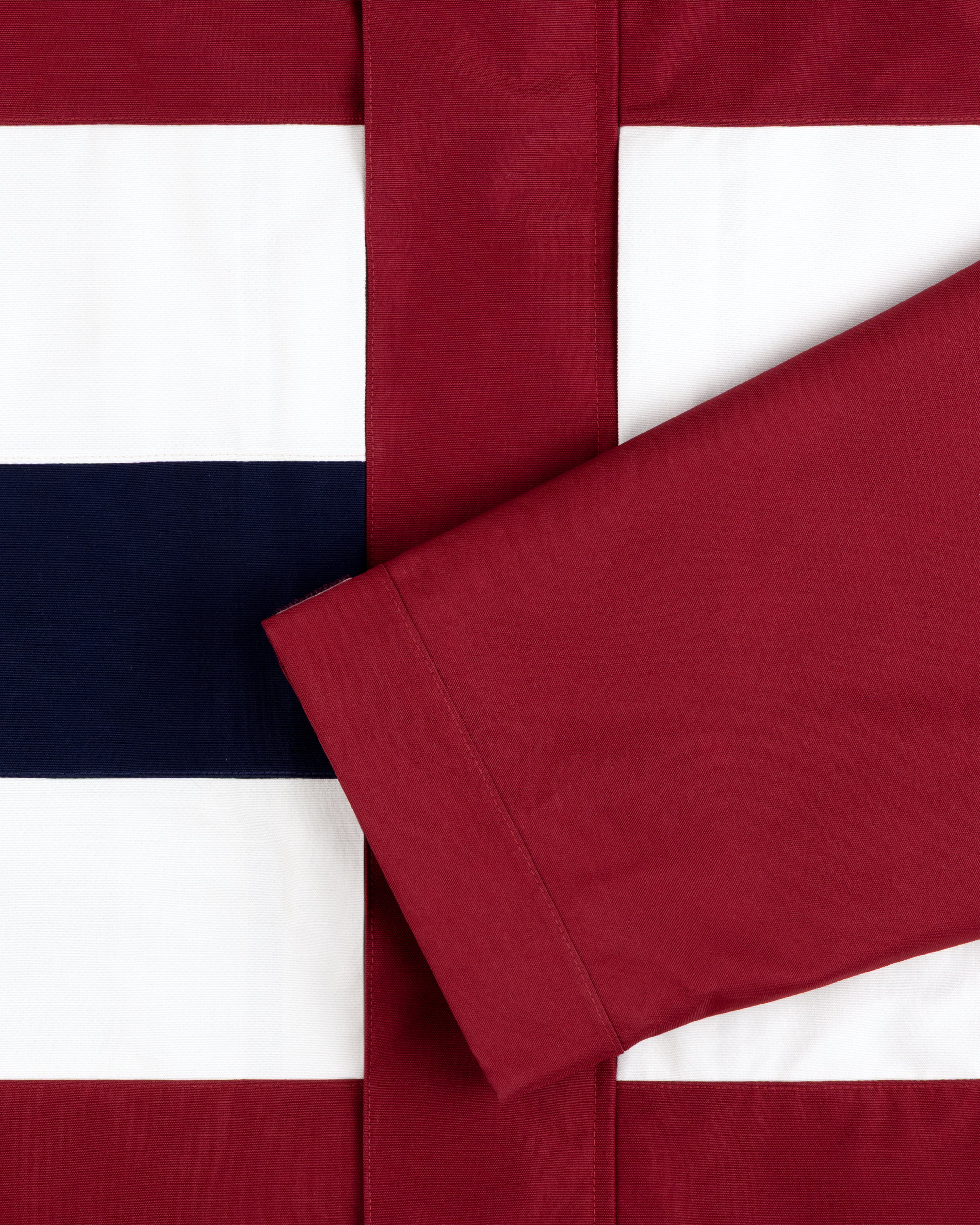 A maroon sleeve rests on a red, white, and navy GORE-TEX Striped Sailing Jacket.