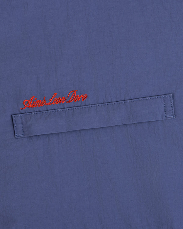 Blue Fleece Lined Sport Windbreaker with a stitched flap and Aimé Leon Dore embroidered in red cursive above.