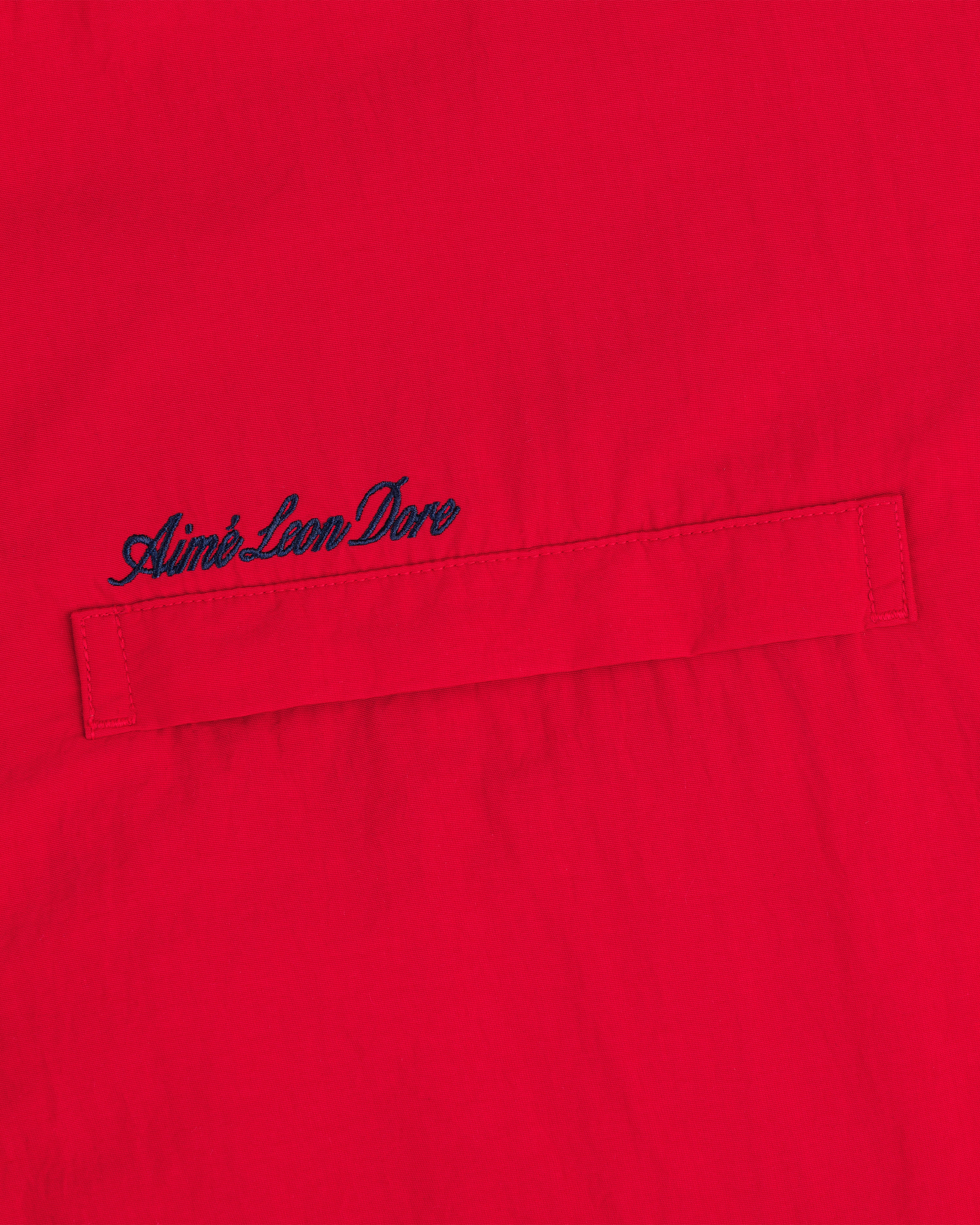 Red Fleece Lined Sport Windbreaker with a horizontal stitched pocket and navy Aimé Leon Dore embroidery above it.