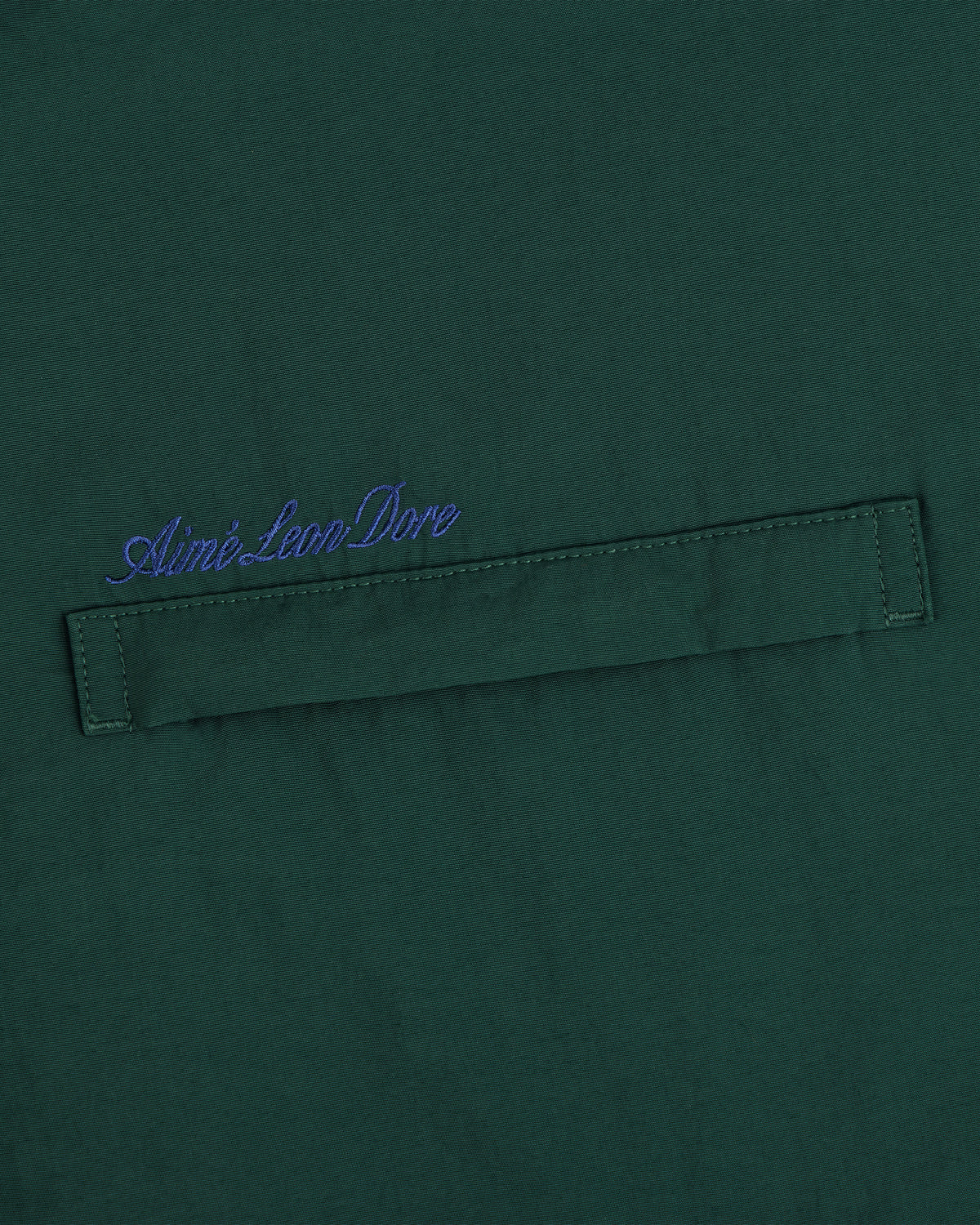 Green fleece lined sport windbreaker with horizontal stitched strip and blue Aimé Leon Dore script embroidered above.