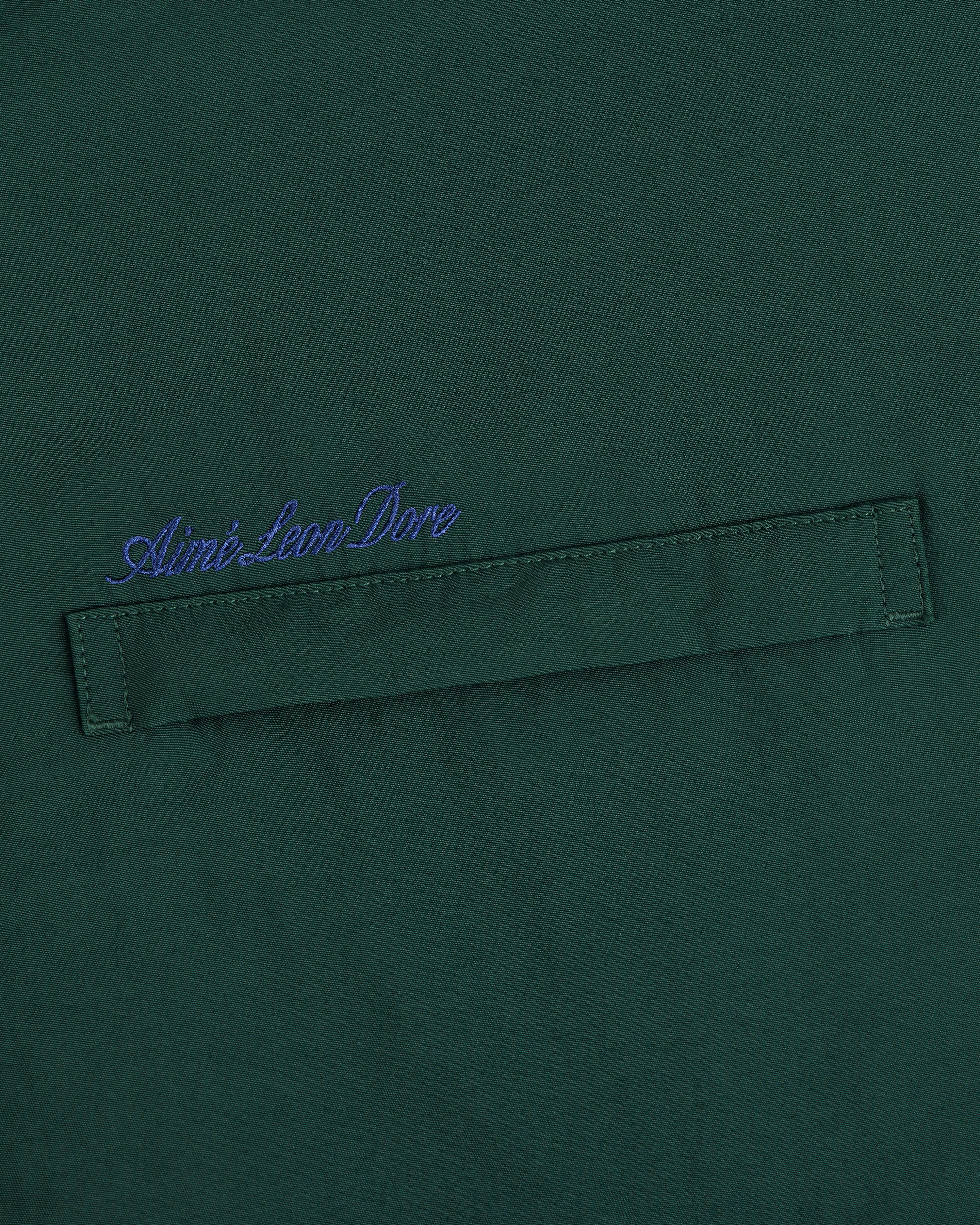 Green fleece lined sport windbreaker with horizontal stitched strip and blue Aimé Leon Dore script embroidered above.