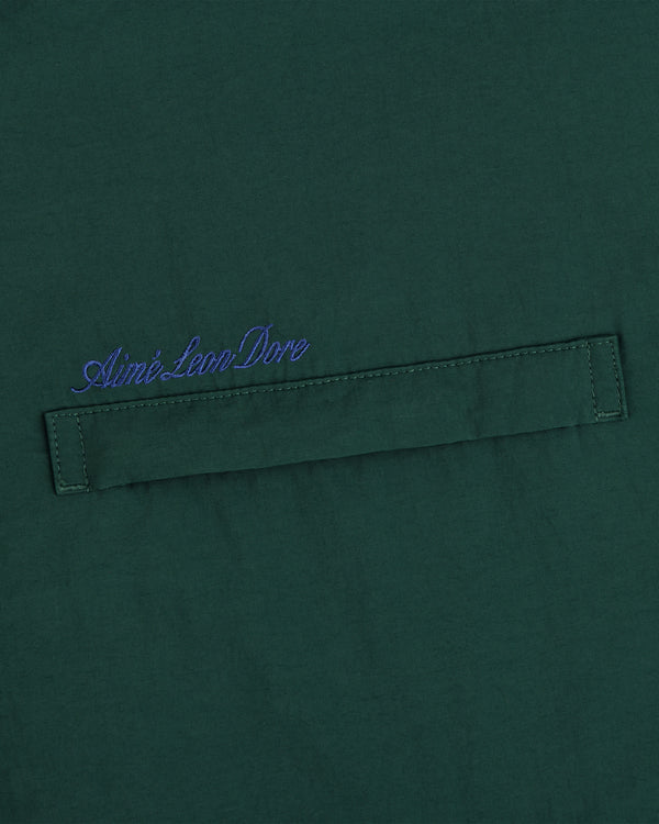 Green fleece lined sport windbreaker with horizontal stitched strip and blue Aimé Leon Dore script embroidered above.