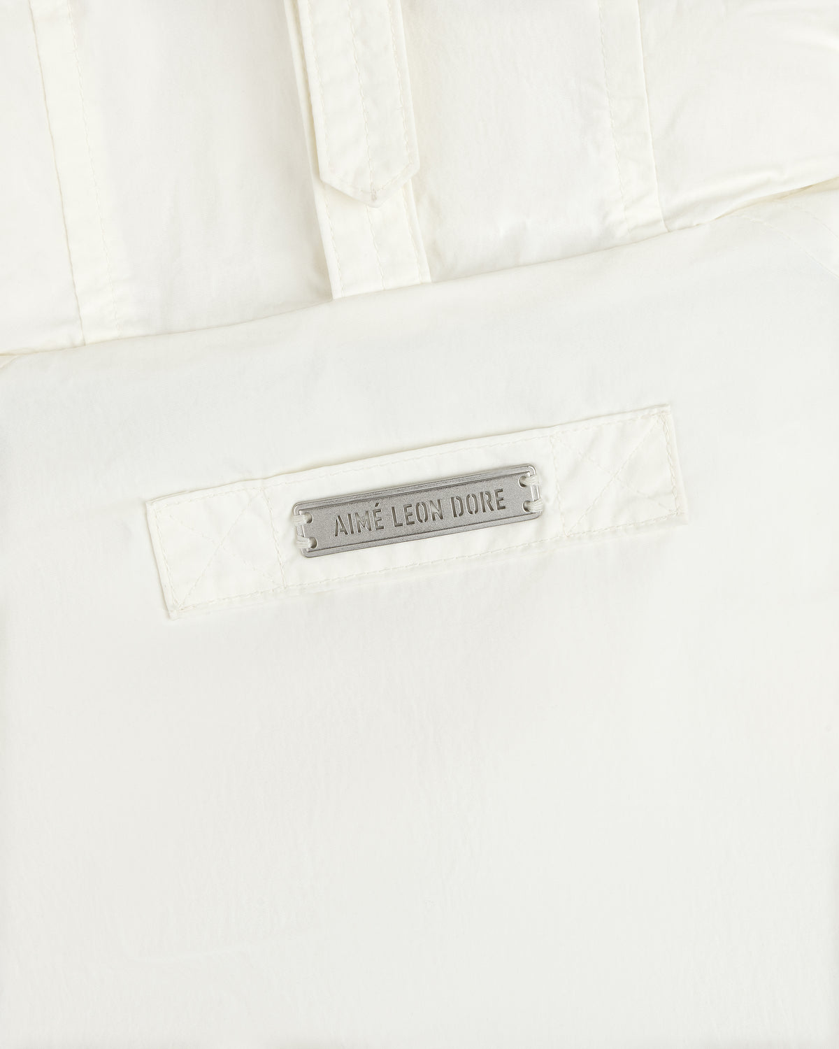 Off-white Down-Filled Surplus Parka featuring a rectangular metal plaque engraved with the text Aime Leon Dore.