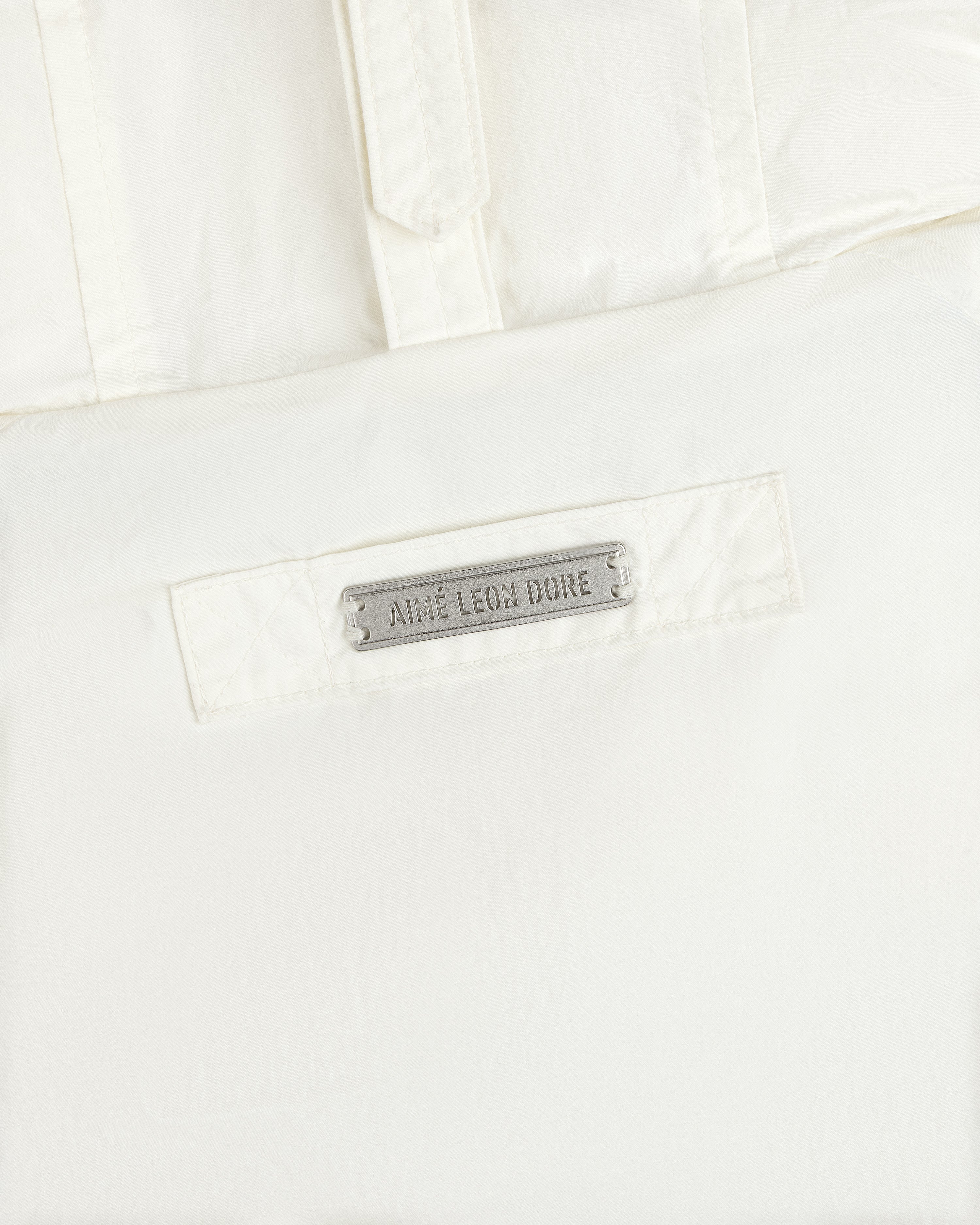 Off-white Down-Filled Surplus Parka featuring a rectangular metal plaque engraved with the text Aime Leon Dore.