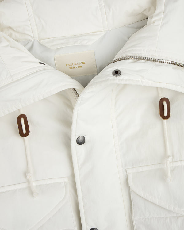 Close-up of a white Down-Filled Surplus Parka with a metal zipper, snap buttons, and two brown drawstring toggles.