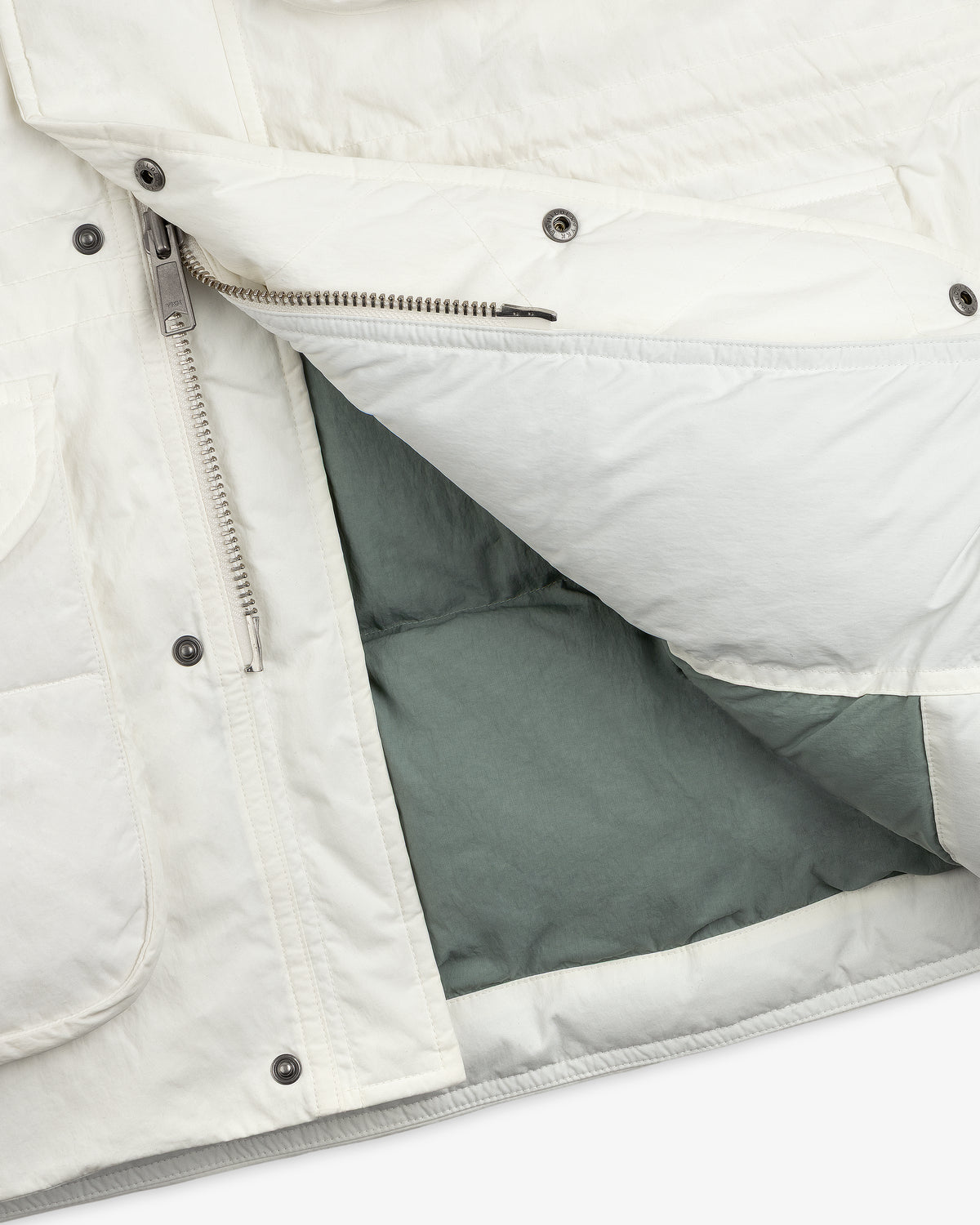 Close-up of an unzipped white Down-Filled Surplus Parka with a gray lining and metal snap buttons.