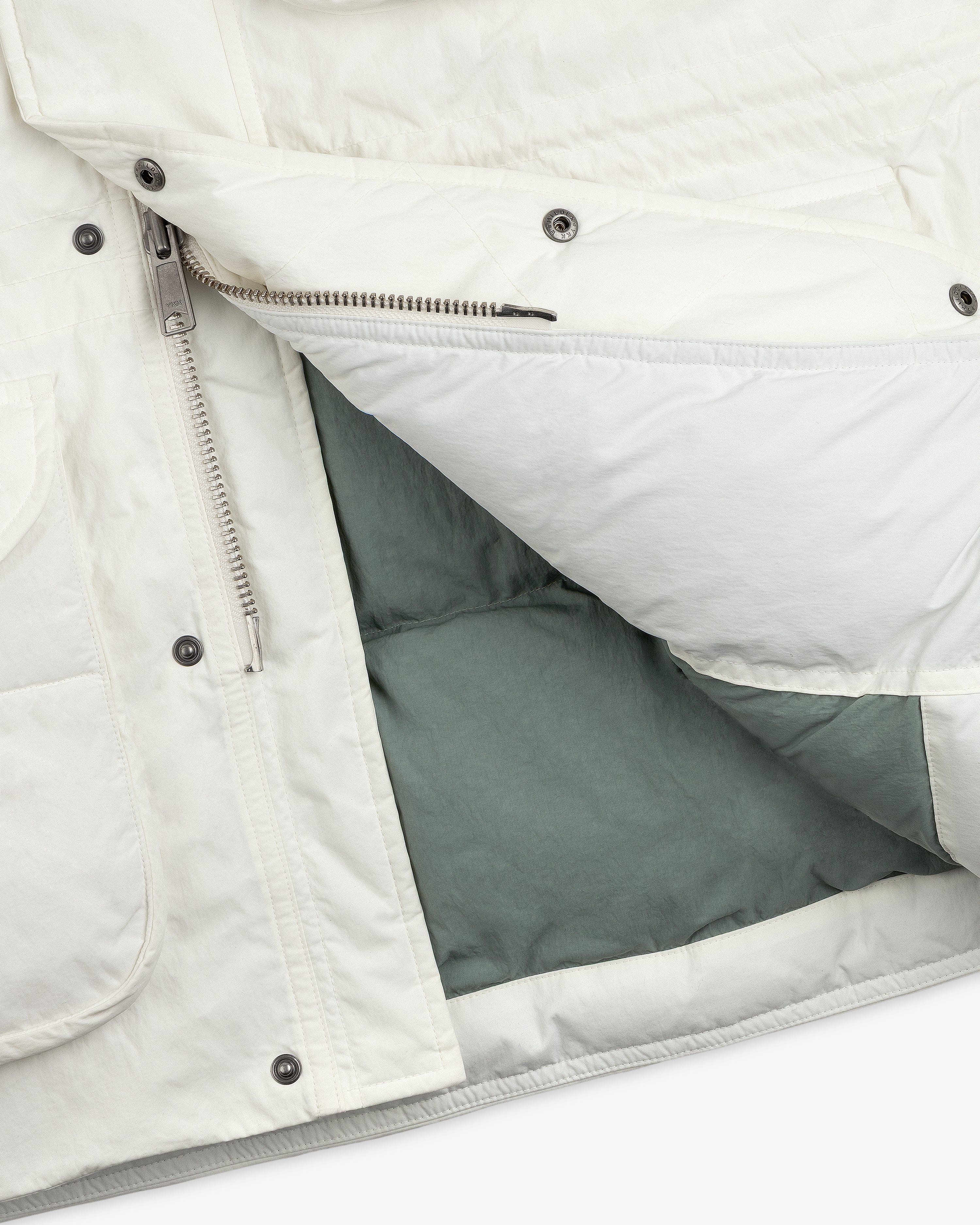 Close-up of an unzipped white Down-Filled Surplus Parka with a gray lining and metal snap buttons.