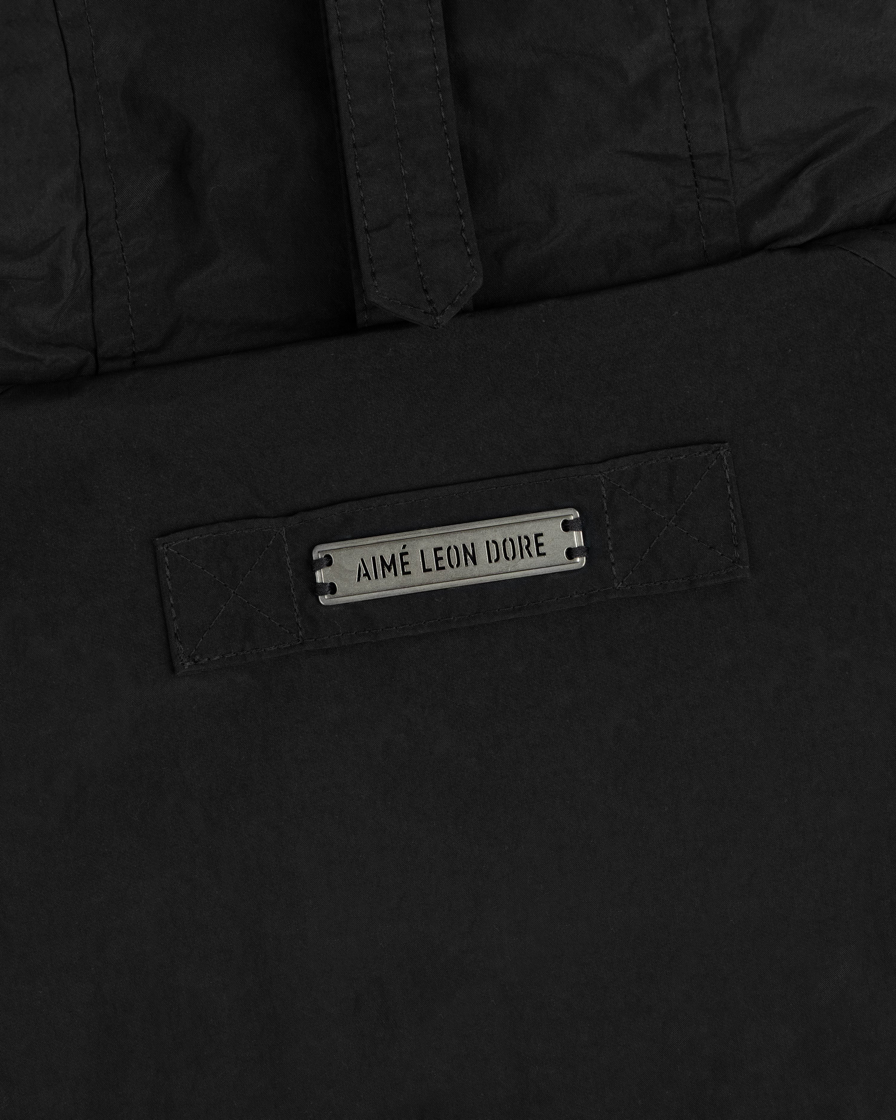 Black Down-Filled Surplus Parka with a hood and a metal Aimé Leon Dore branded plate.