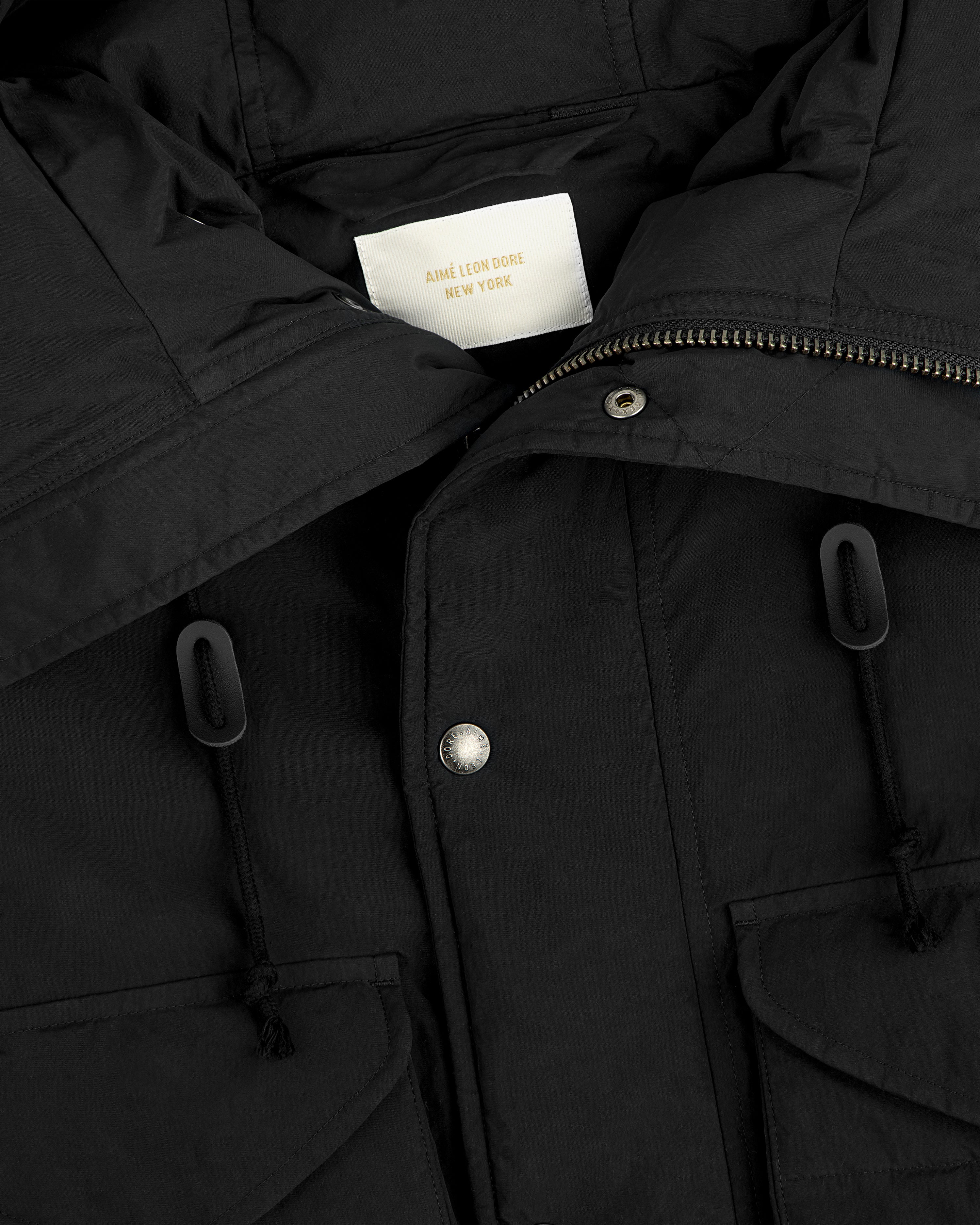 Close-up of a black Down-Filled Surplus Parka with a high collar, snap buttons, and two pockets with drawstring toggles.