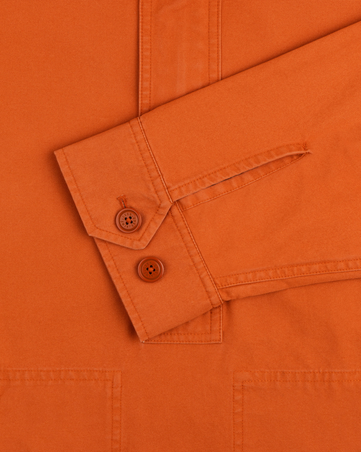 Close-up of the Garment Washed Anorak orange long-sleeve shirt cuff with two matching buttons.