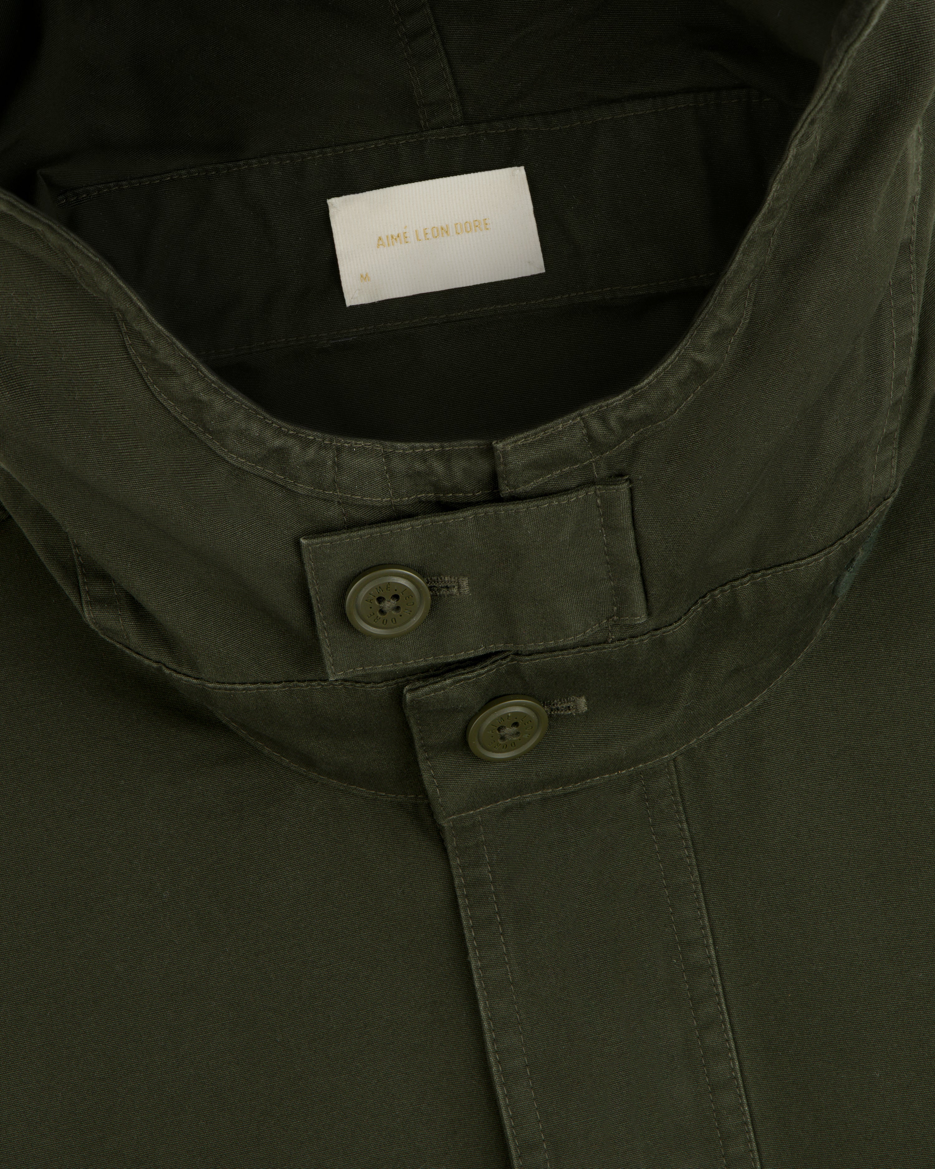 Close-up of the olive green collar and buttoned placket of a Garment Washed Anorak.